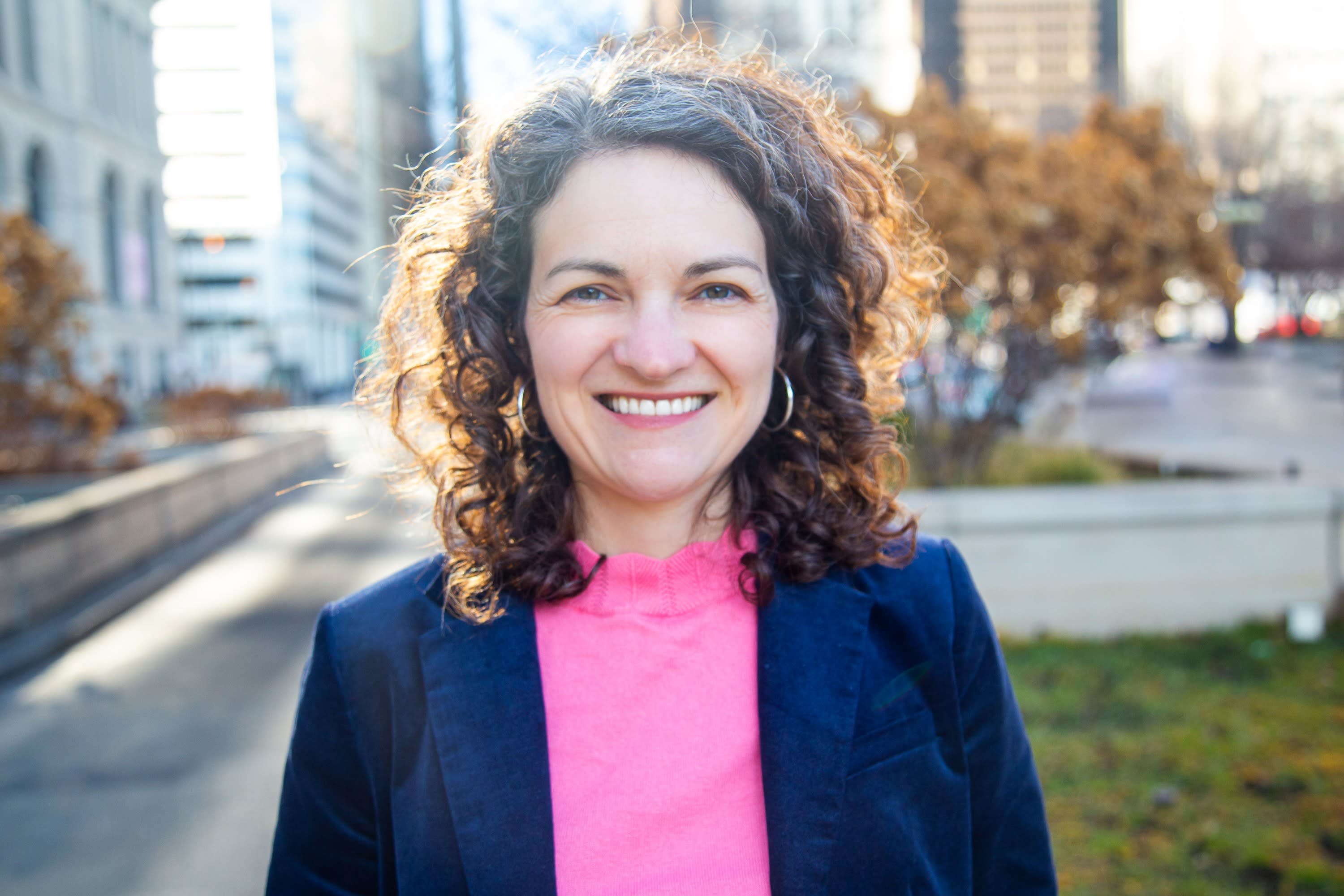 Photo of a woman in a bright pink shirt and blazer