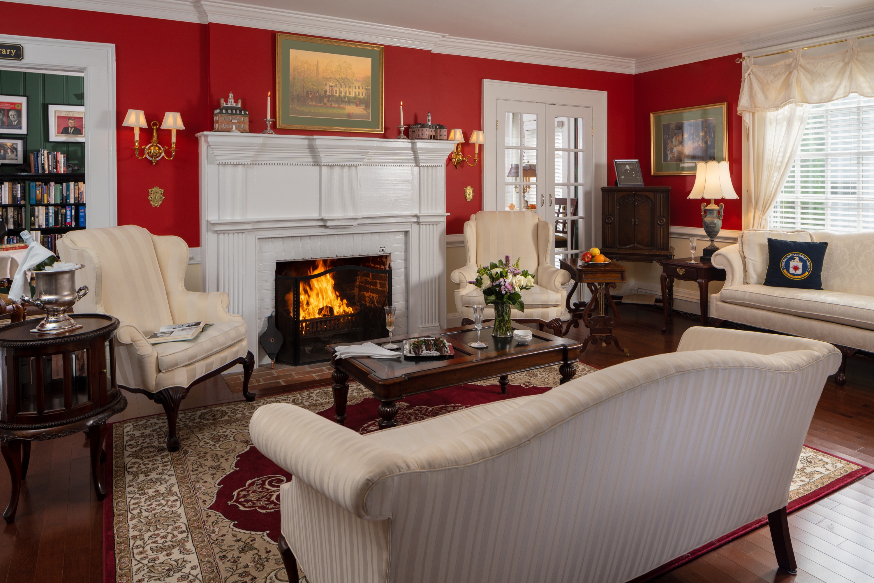 wood burning fireplace in reception room with white chairs and sofas