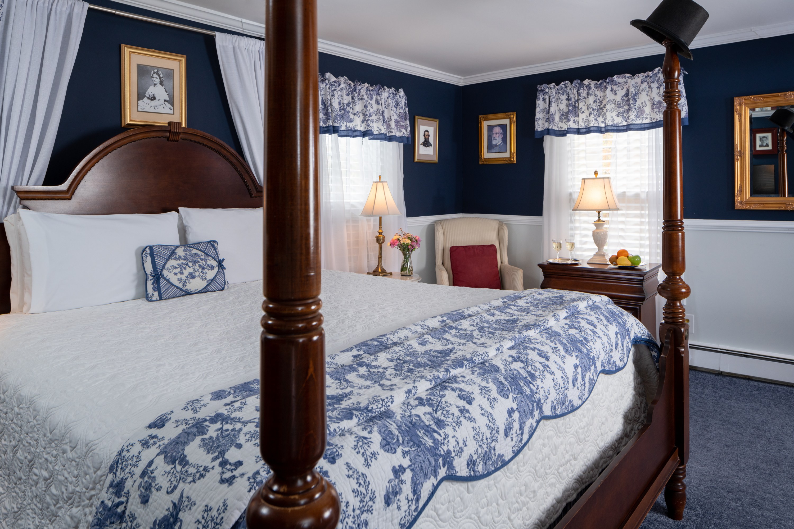 Four poster King bed with white comforter, blue carpeting