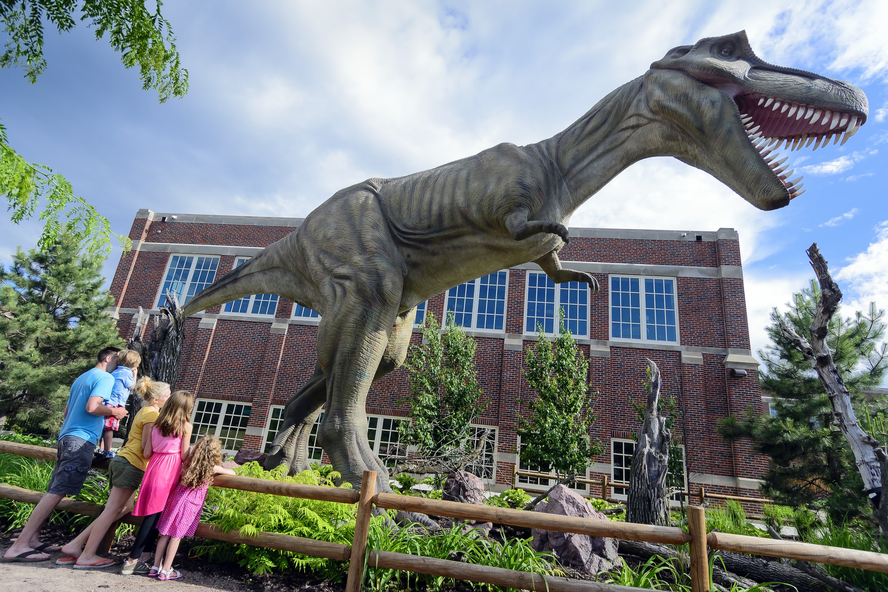 Family standing in front of a life-size animatronic t. rex dinosaur.