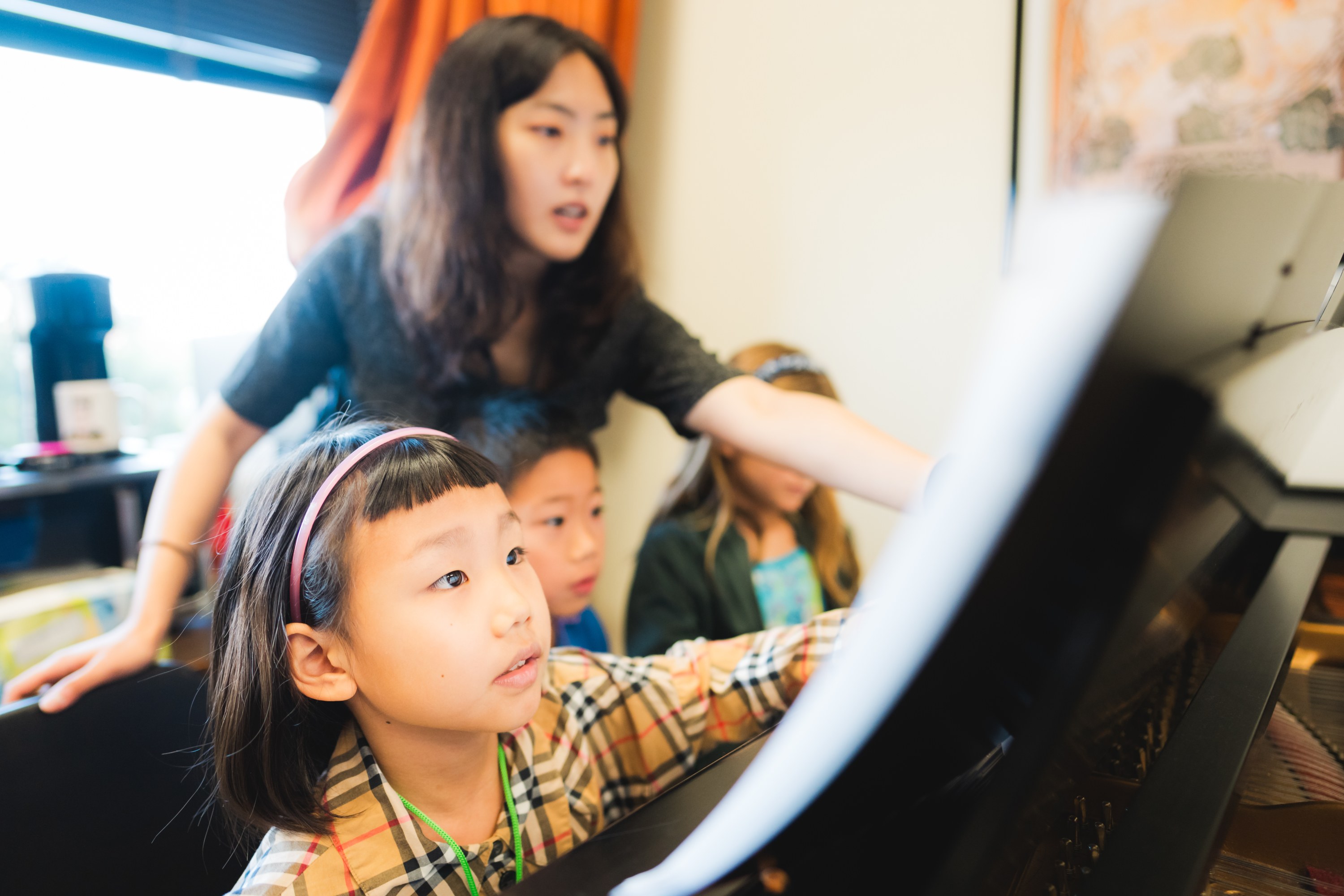 Music teacher coaching young piano students