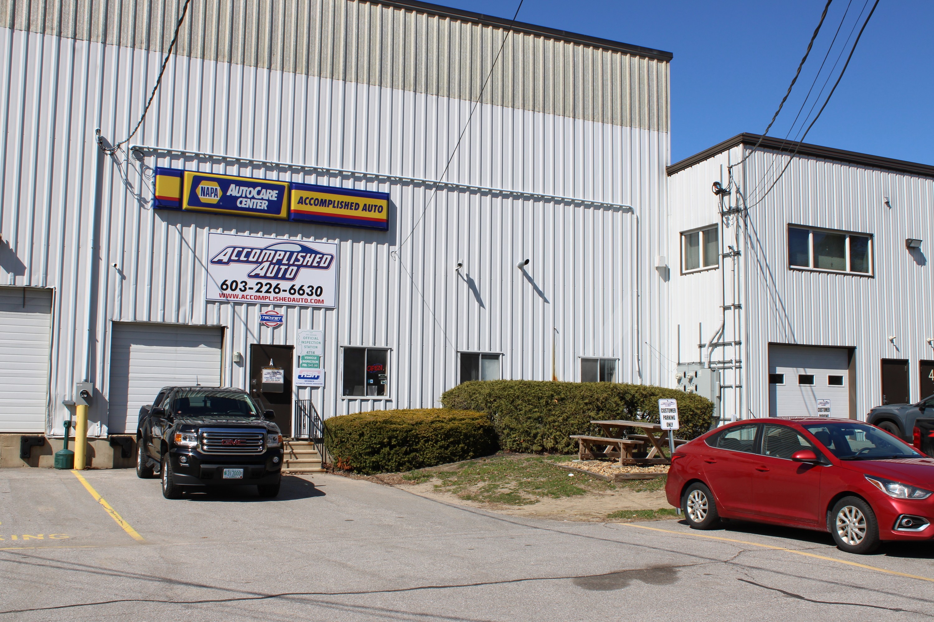 Customer entrance for Accomplished Auto with vehicles out front and signage