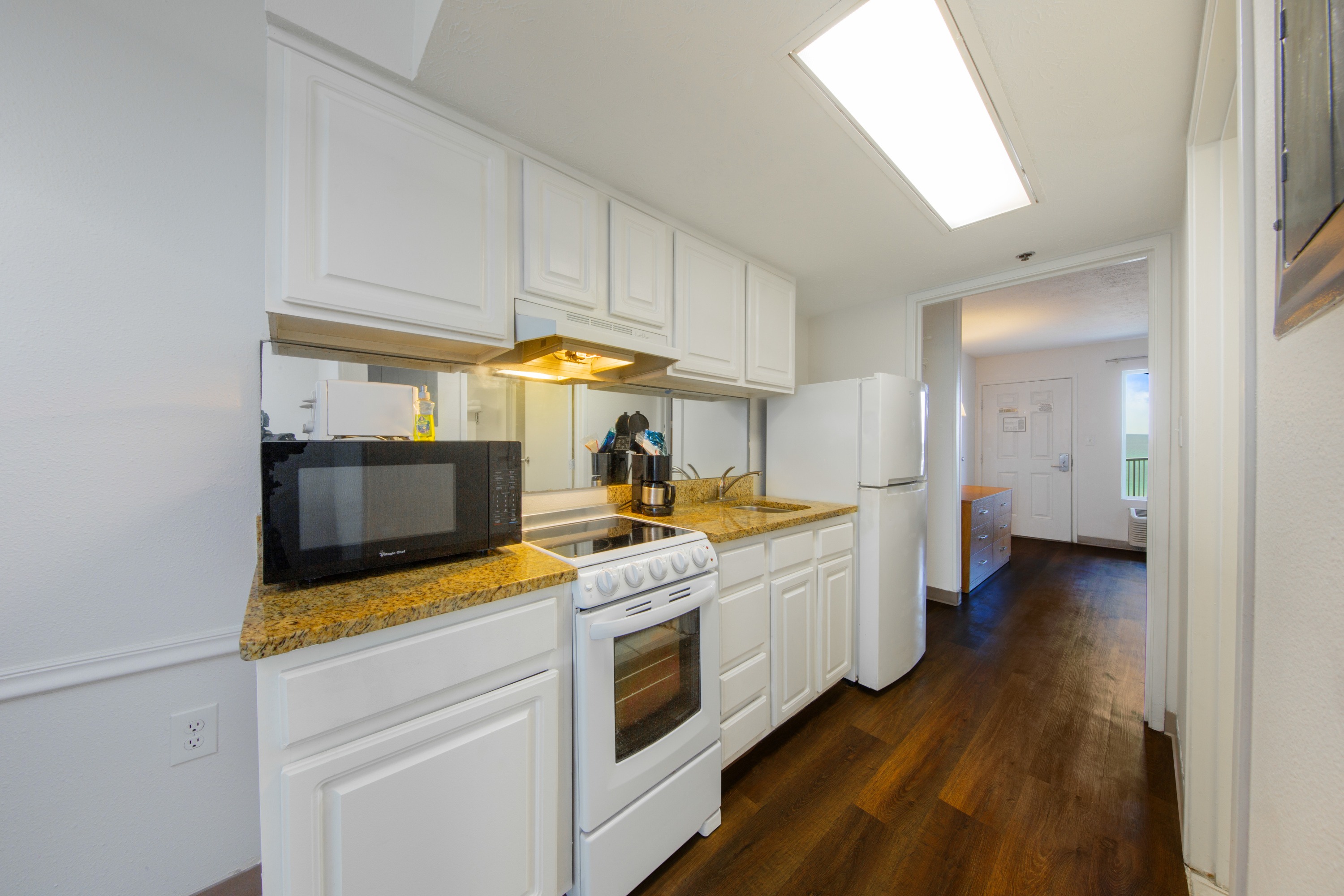 hotel kitchen with microwave, stove, sink and refridgerator