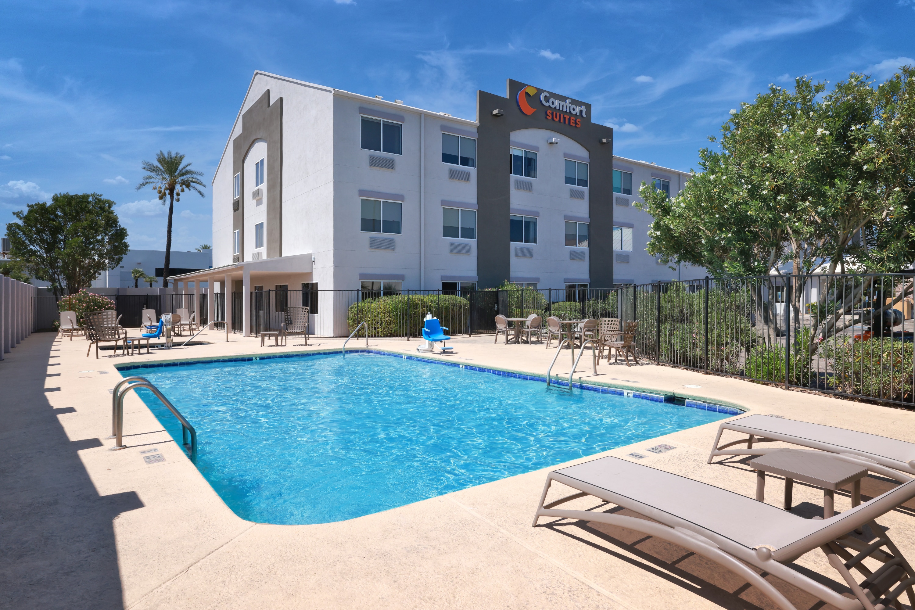Outdoor swimming pool and whirlpool at Comfort Suites Tucson Mall with lounge chairs.