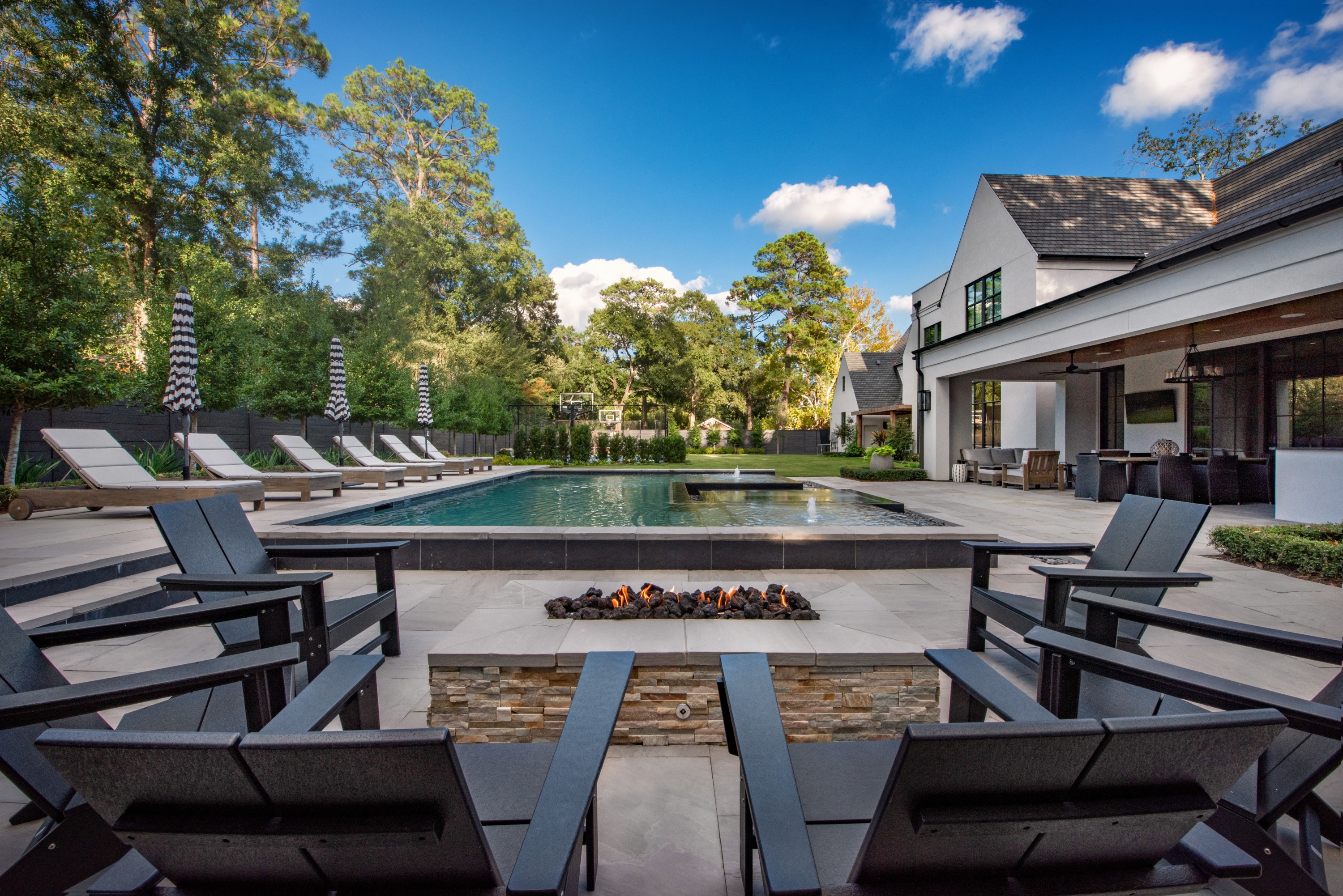 Modern backyard pool with fire pit, lounge seating, and water features by Sunset Pools in Houston, Texas.