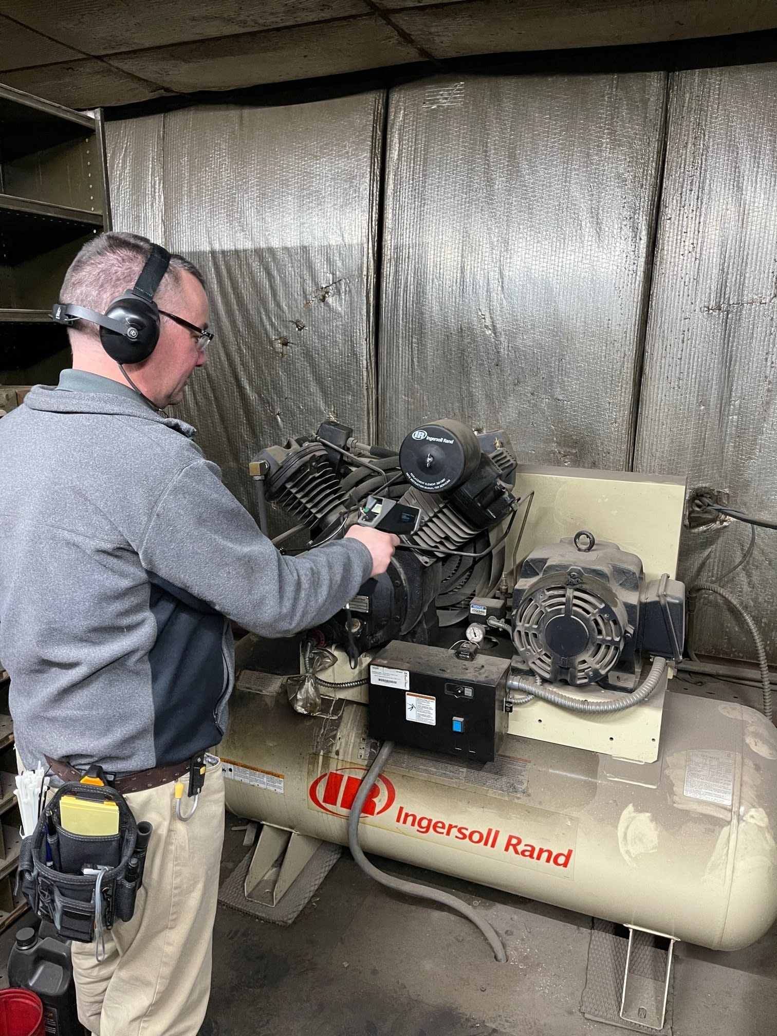 man with headphones handling an industrial air compressor
