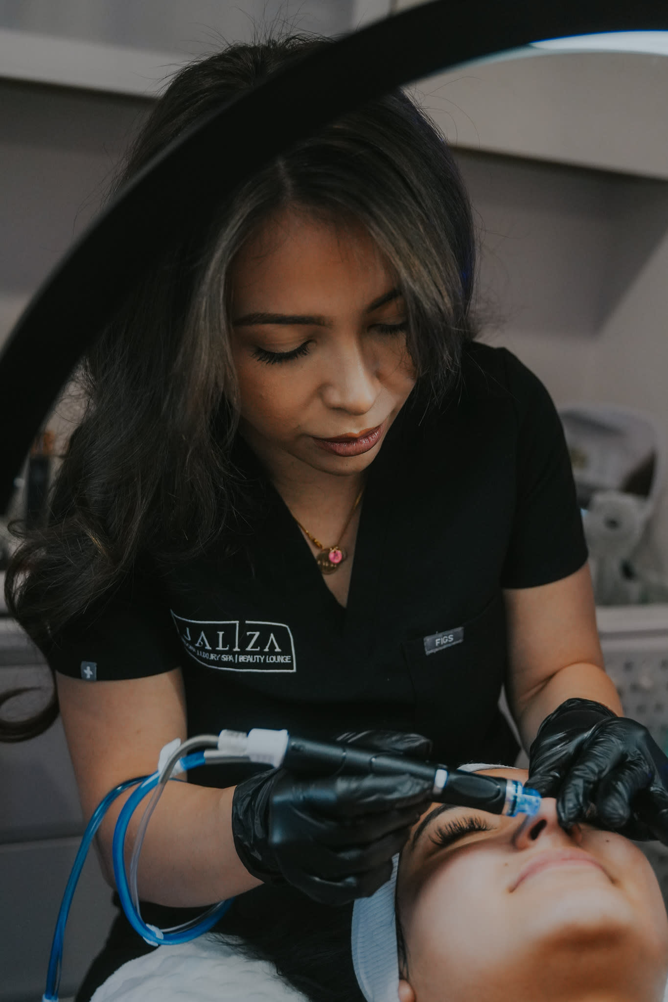 Esthetician at Jaliza Sedona Luxury Med Spa wearing black gloves and performing a Hydrafacial treatment on a relaxed client.