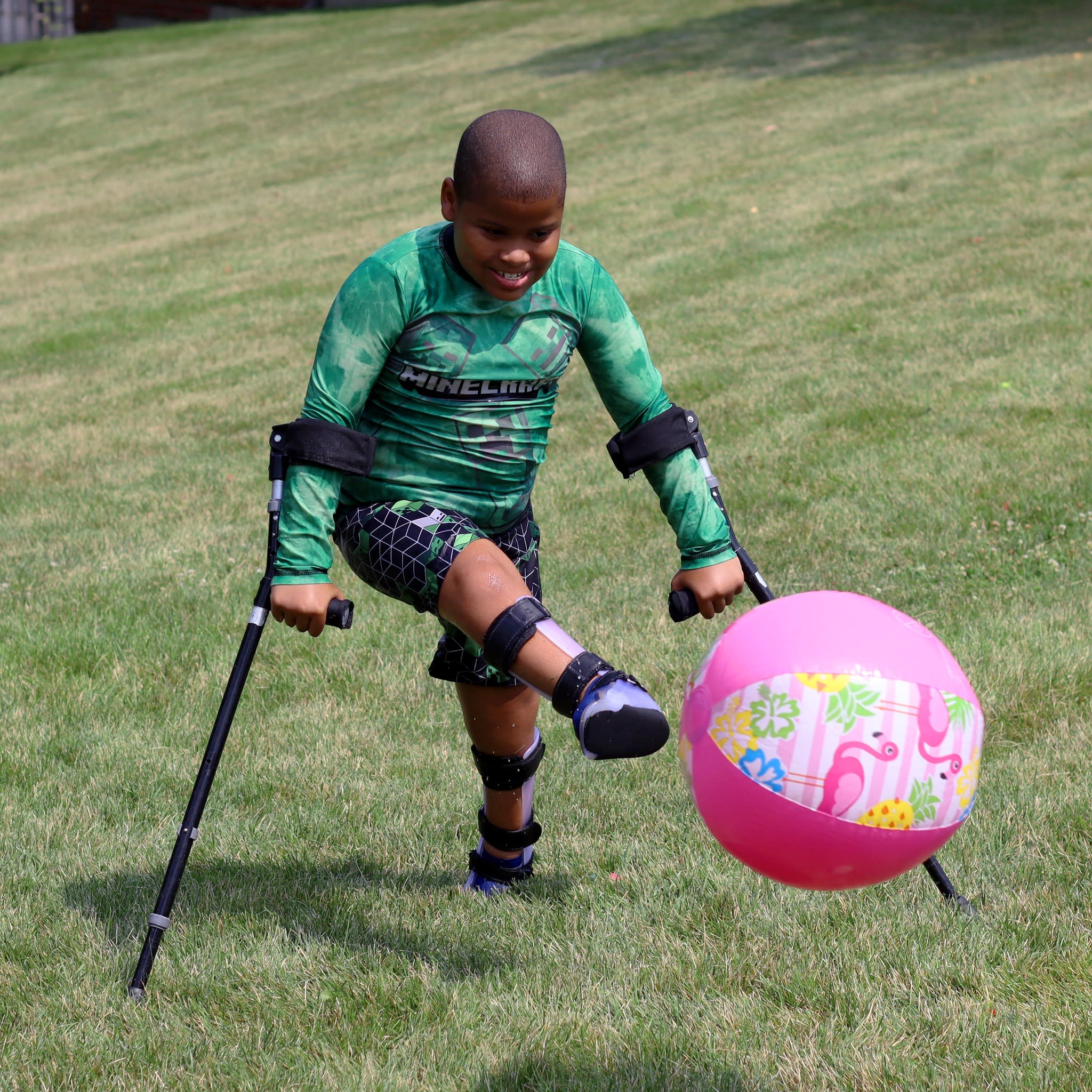 SSSRA day camp participant using crutches and kicking beach ball