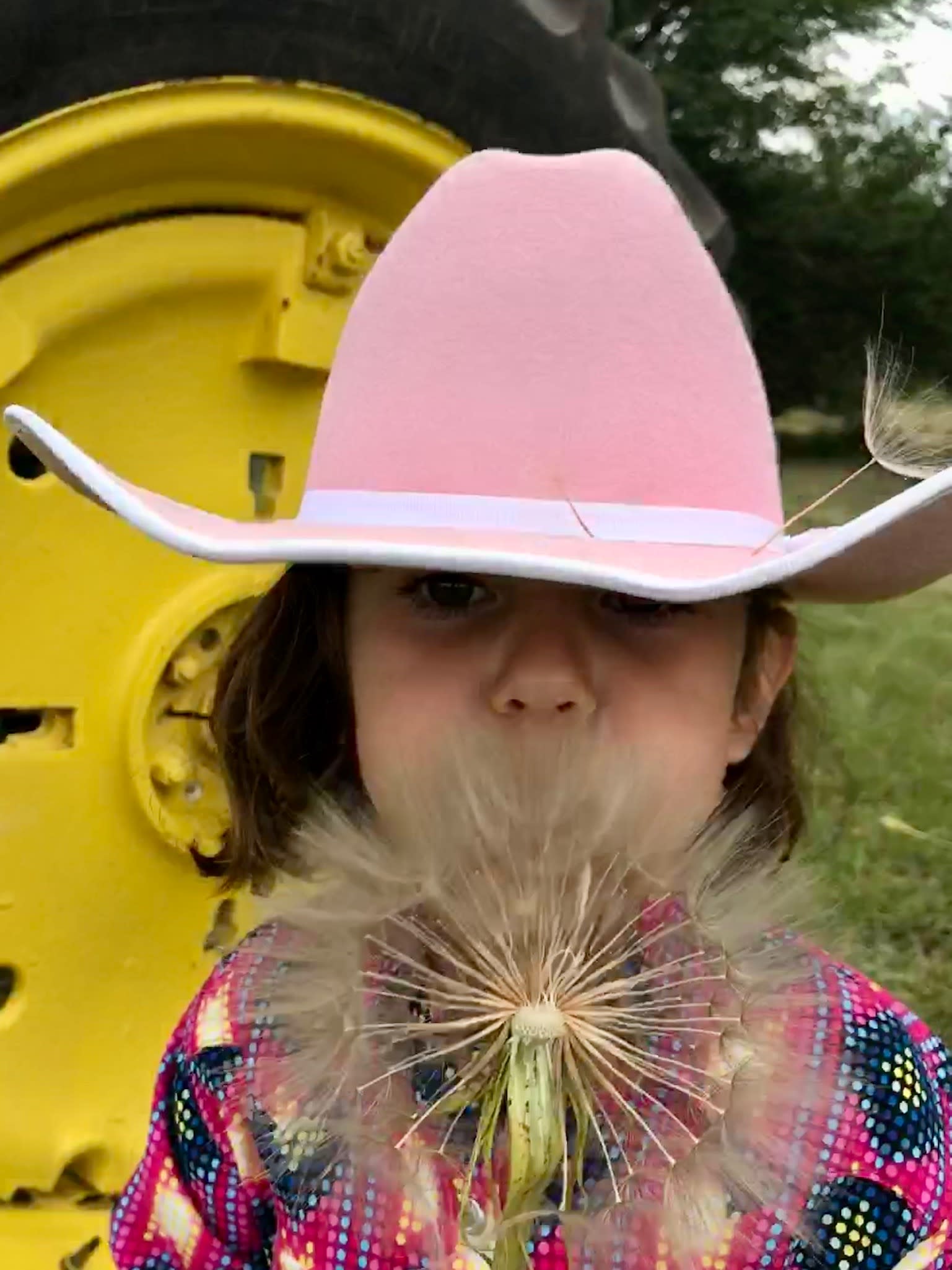 girl in front of tractor with flower