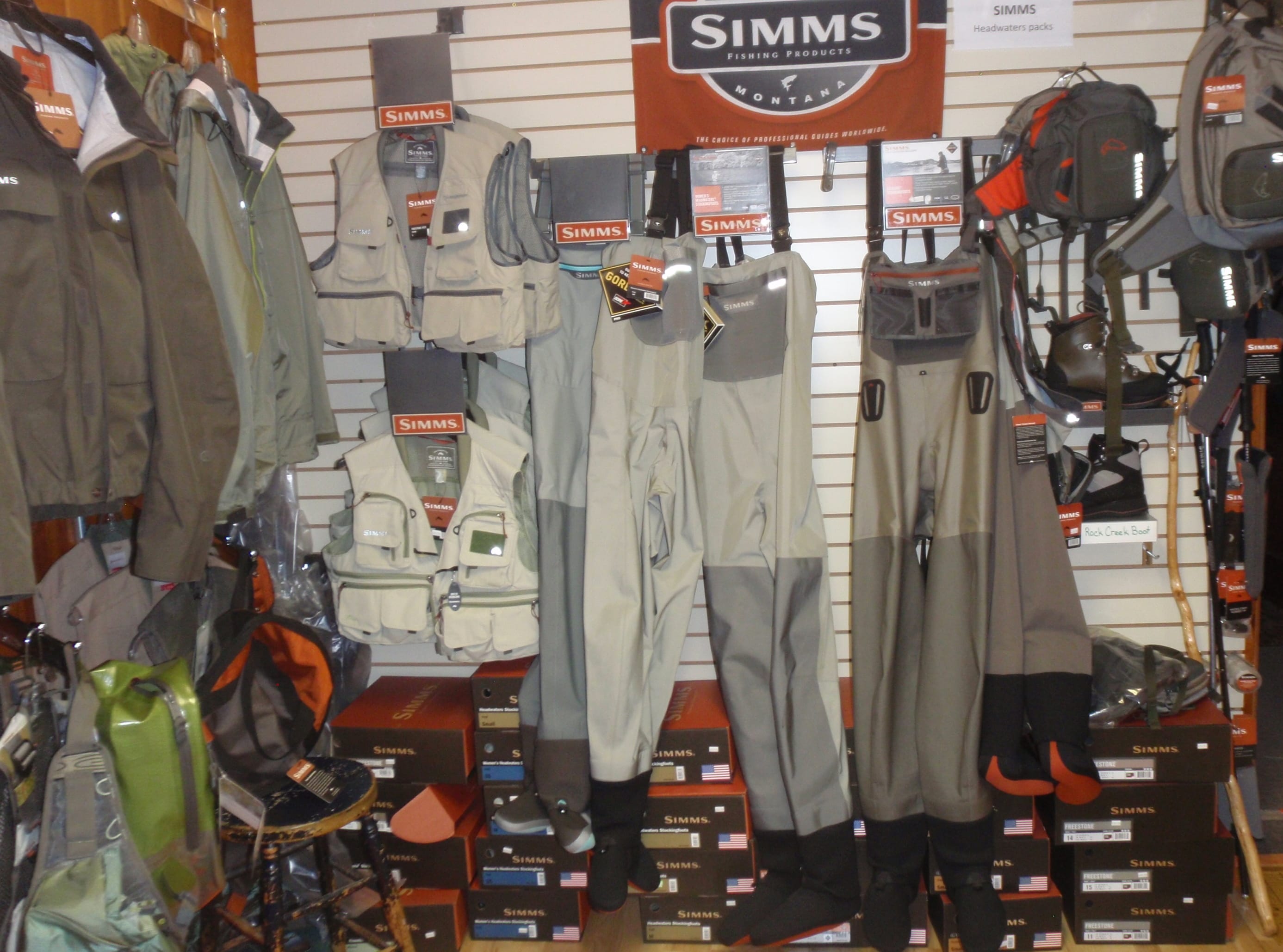 the inside of a fly shop showing waders and boots from the Simms company