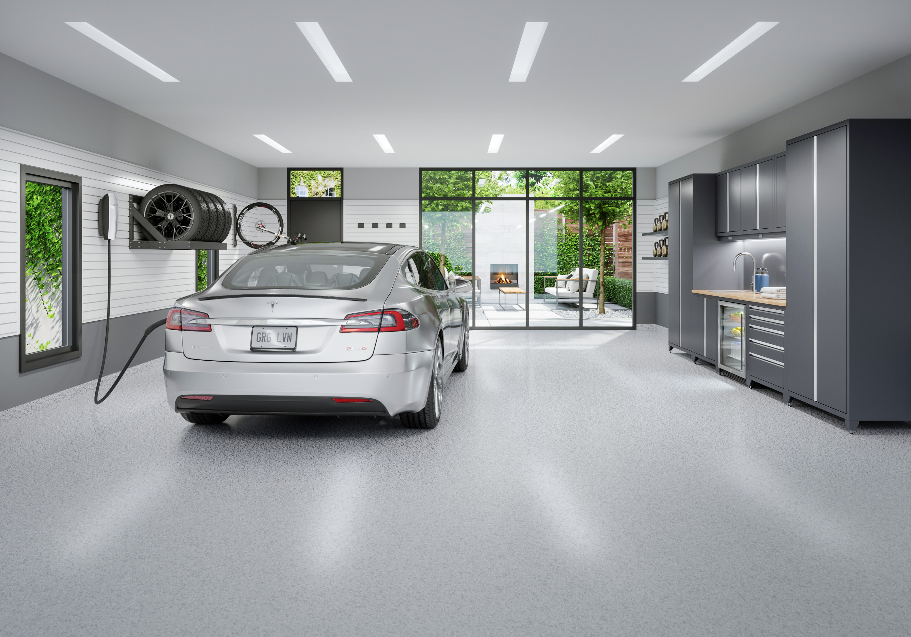 Garage built for EV charging - A spacious garage with flooring, custom cabinets, slatwall, tire racks