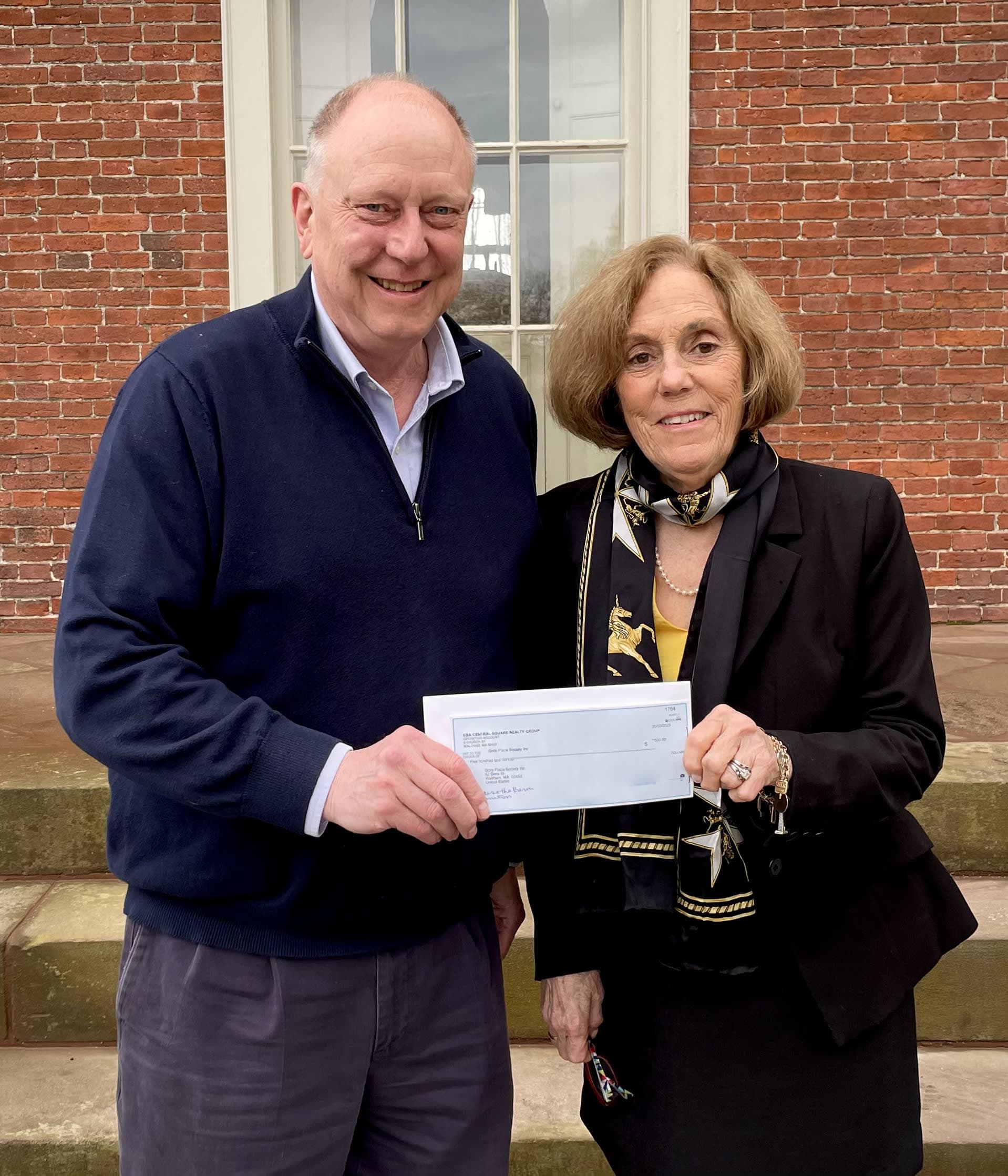 Stewart Woodward of the Metro West HOME Team at Real Broker MA presents a donations to Dina Roberts at Gore Place