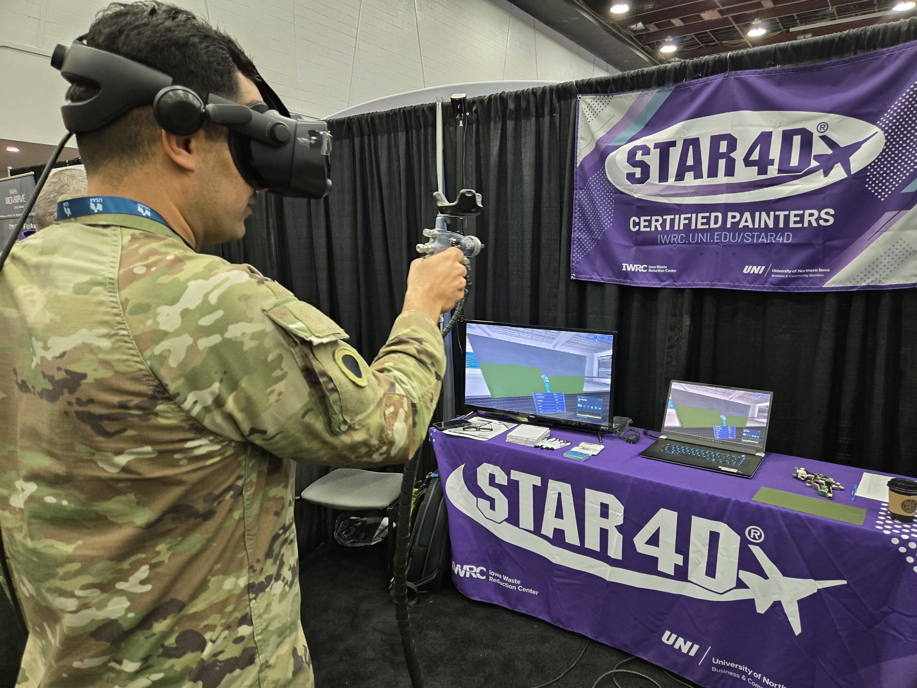 solider wearing a VR headset with paint gun in front of an exhibitor booth