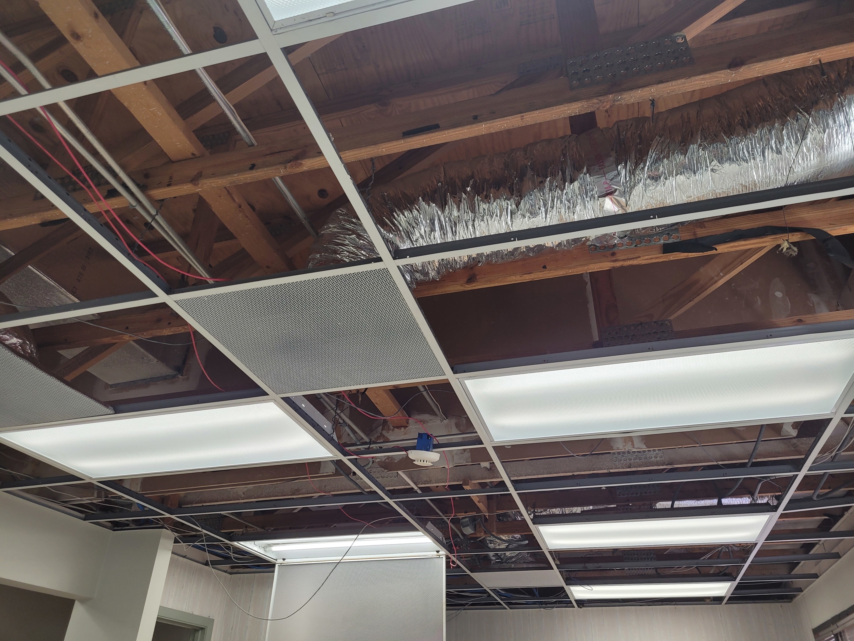 Photo of ceiling with tiles removed, vents and wires exposed