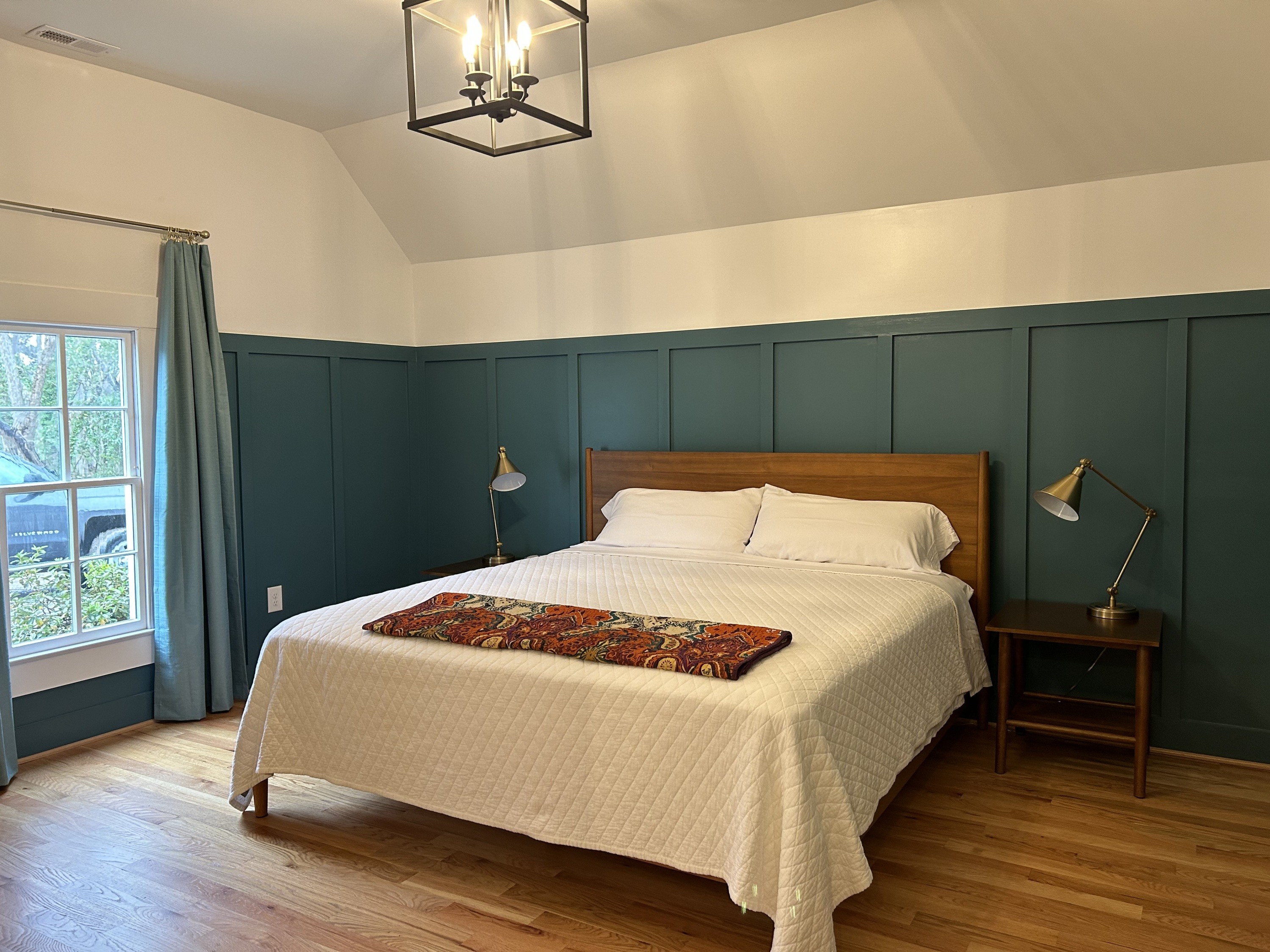 Blue wainscoting wall behind bed and window to the left.