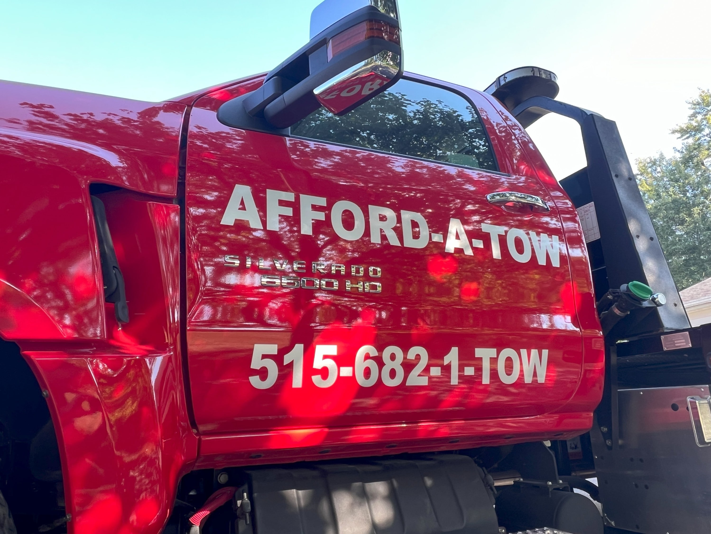Red Afford-A-Tow roll back tow truck door including the phone number 515-682-1869