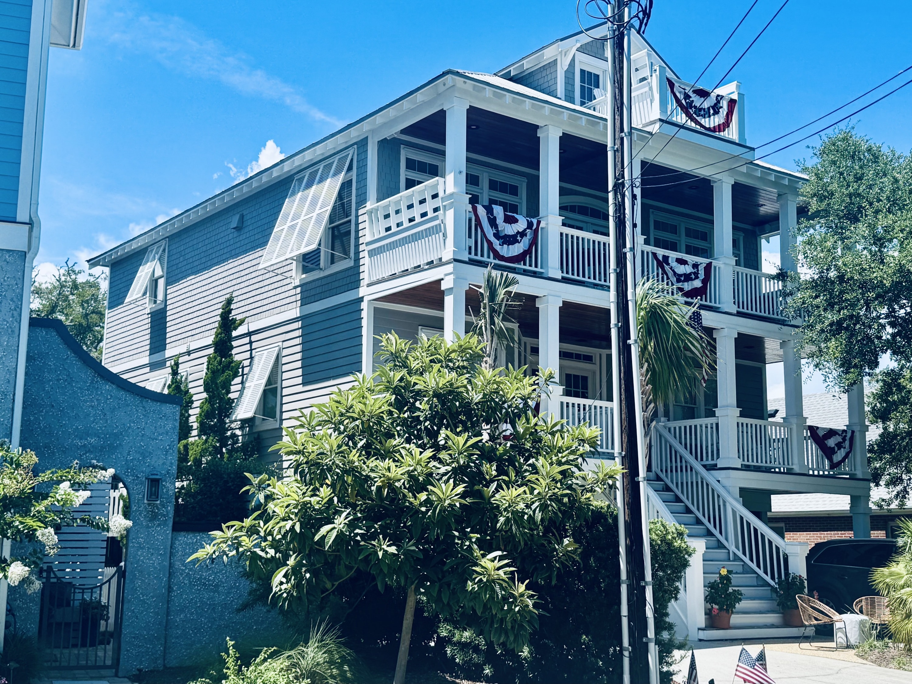 White bahama shutters on a light blue home with flags in Sneads Ferry