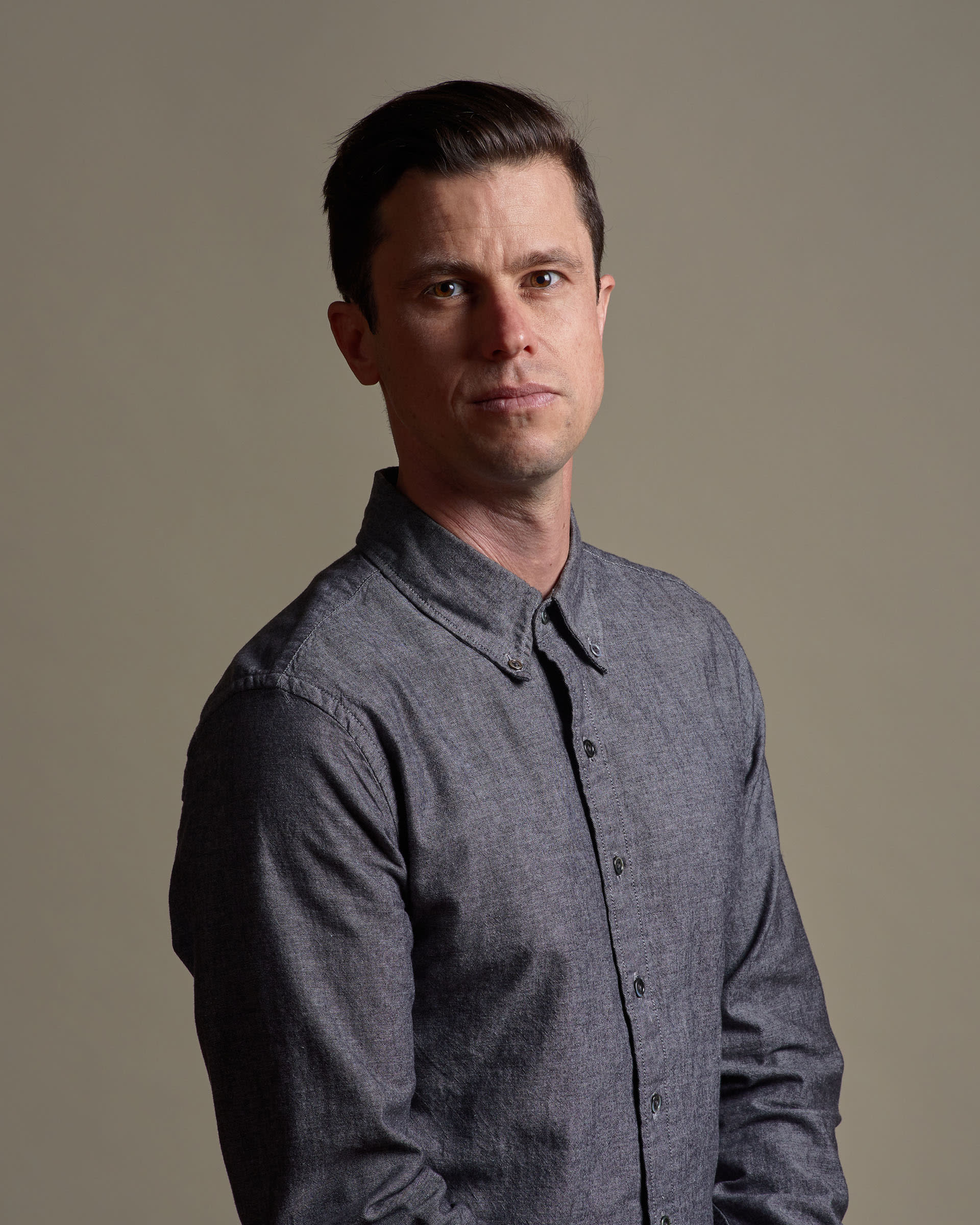 Dan hoyle in a grey button down looking serious