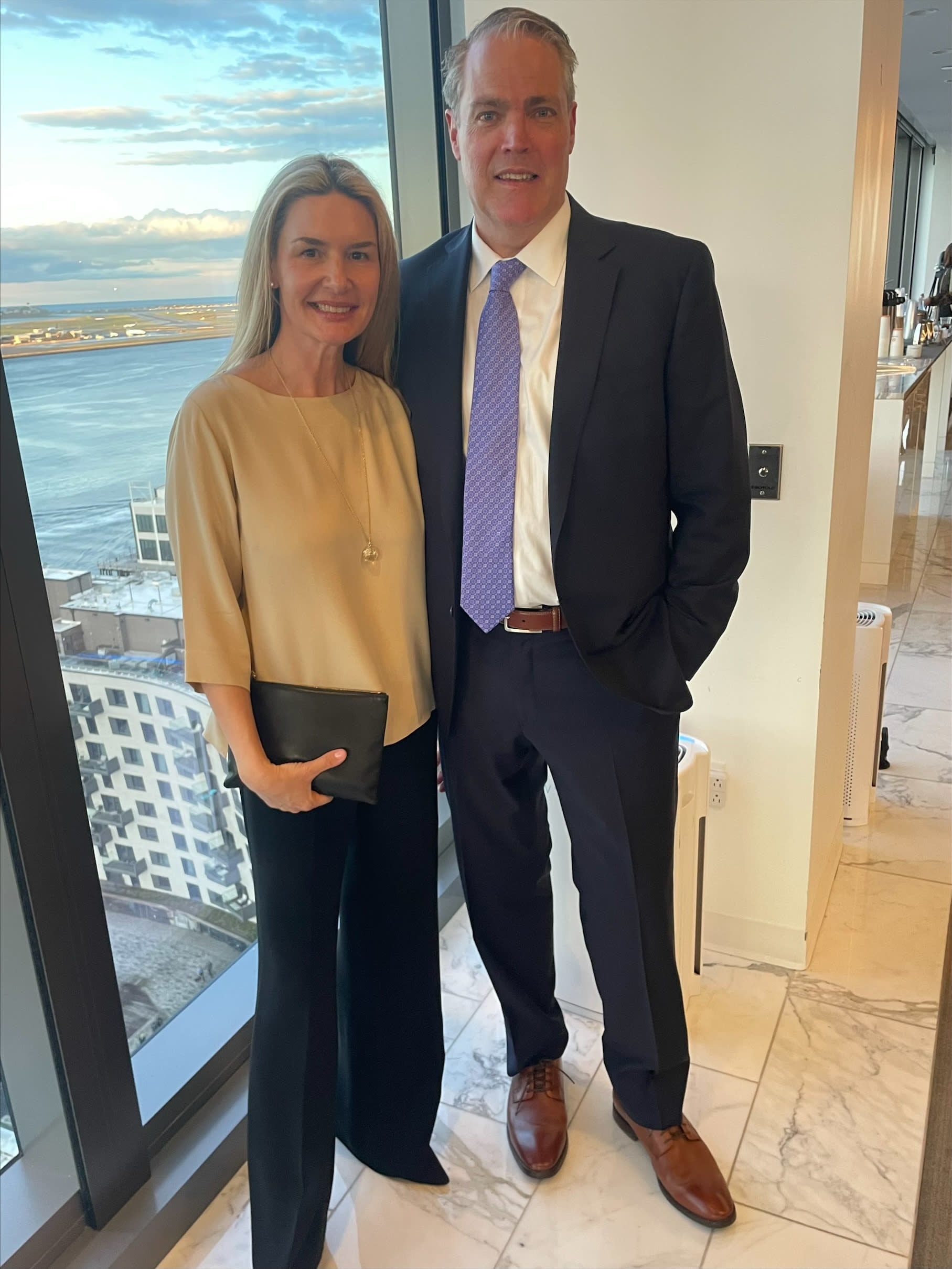 Larry and Sarah Oaks at event location, standing in front of a window showing off the view of the harbor