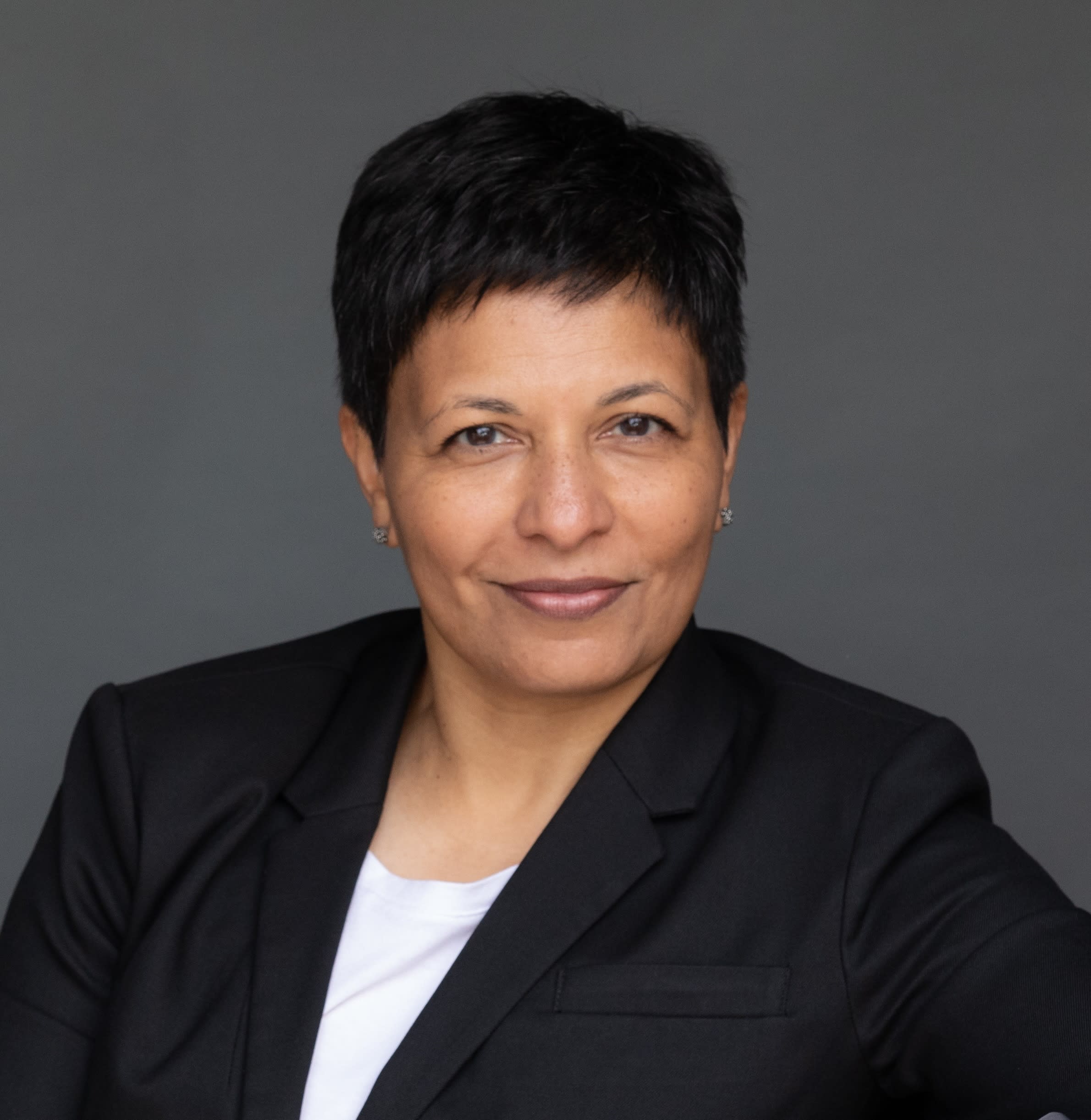 Photo of woman with short black hair wearing black blazer and white top