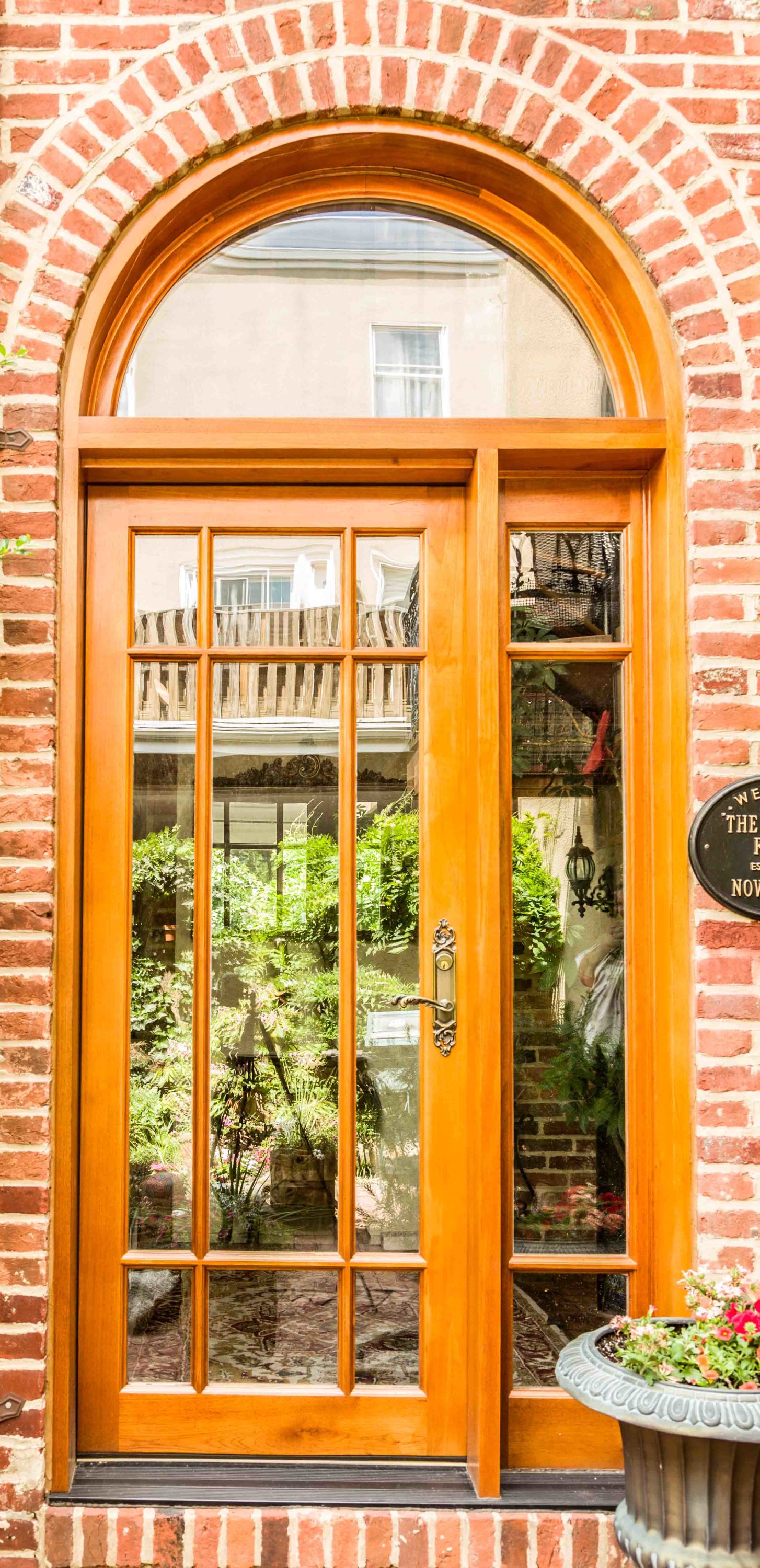 an arched wooden front door with multiple glass panes and an adjacent glass sidelight