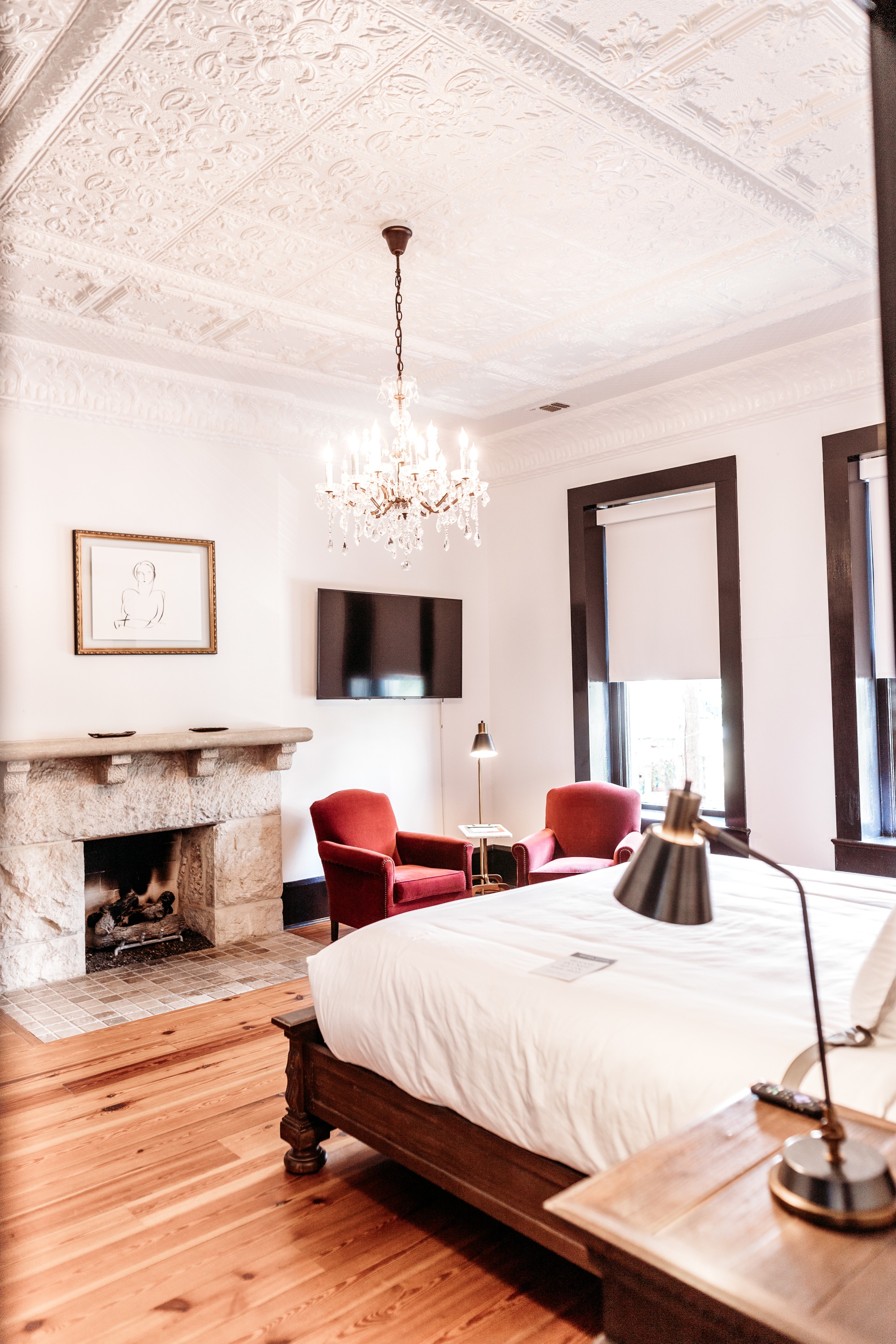 room with king bed, fireplace, tv, two chairs