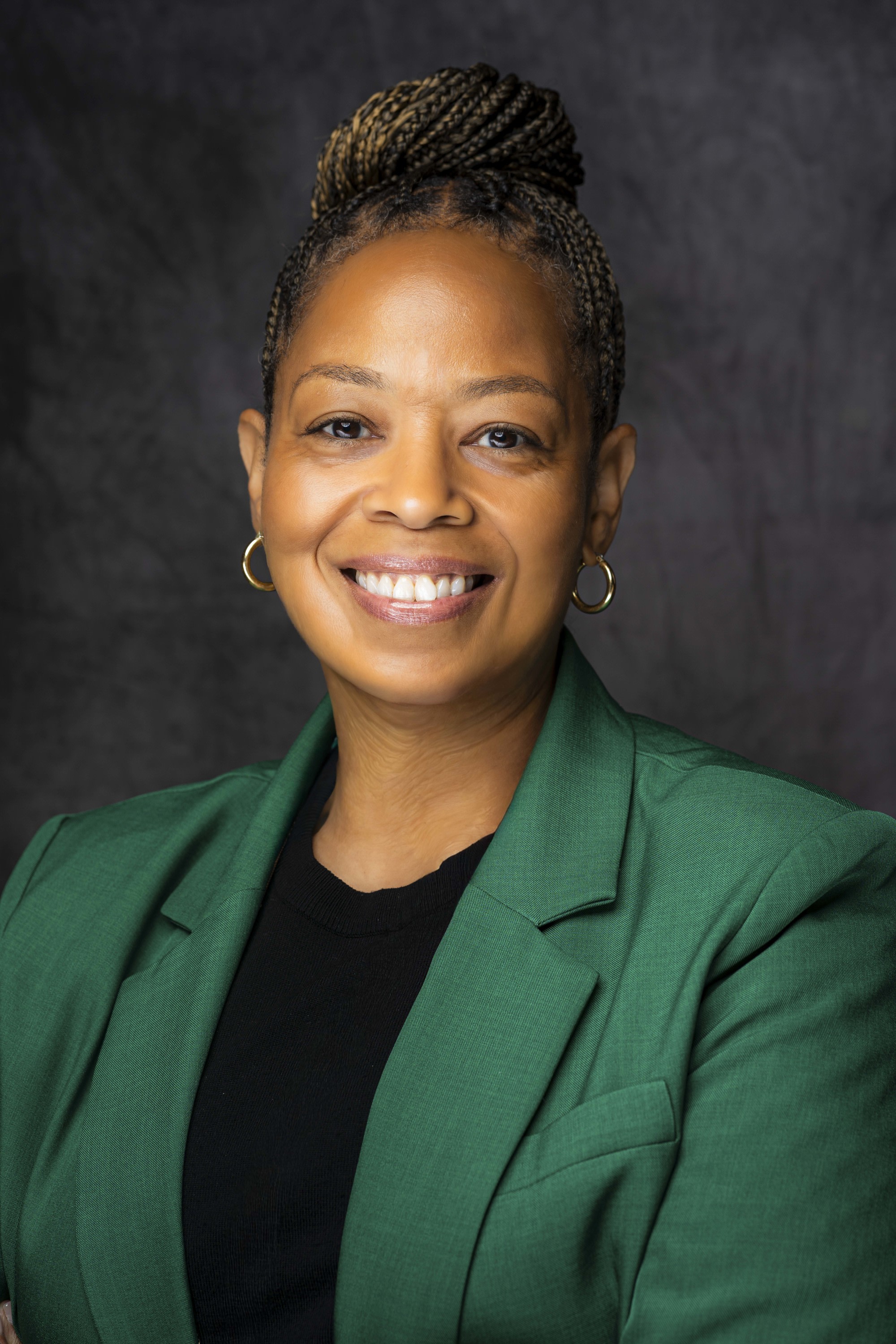 Smiling woman wearing a black top with a green jacket.