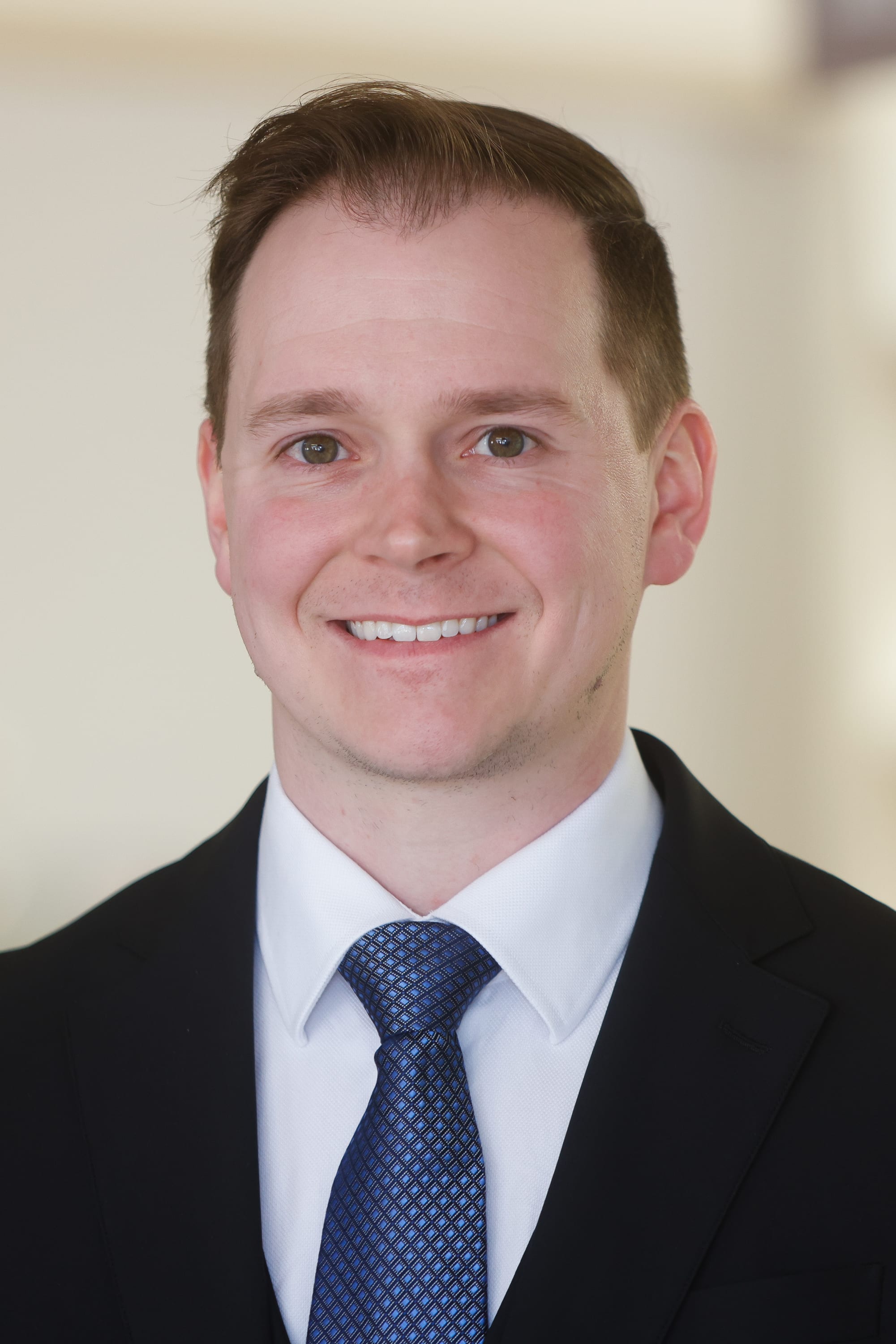 One smiling person in a suit in front of a blurred background
