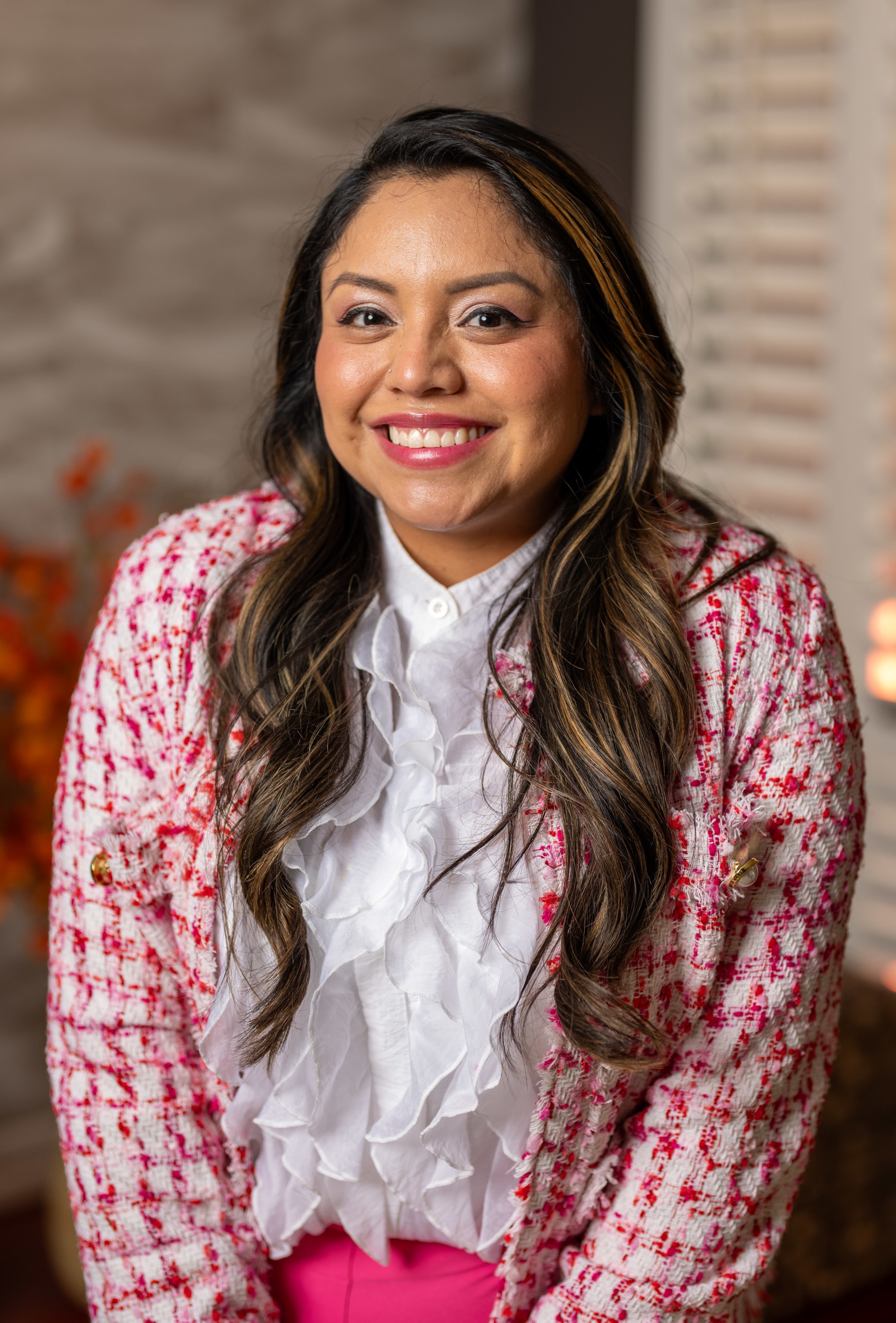 Photo of Adriana Gonzalez wearing a white blouse with pink pants and tweed blazer.