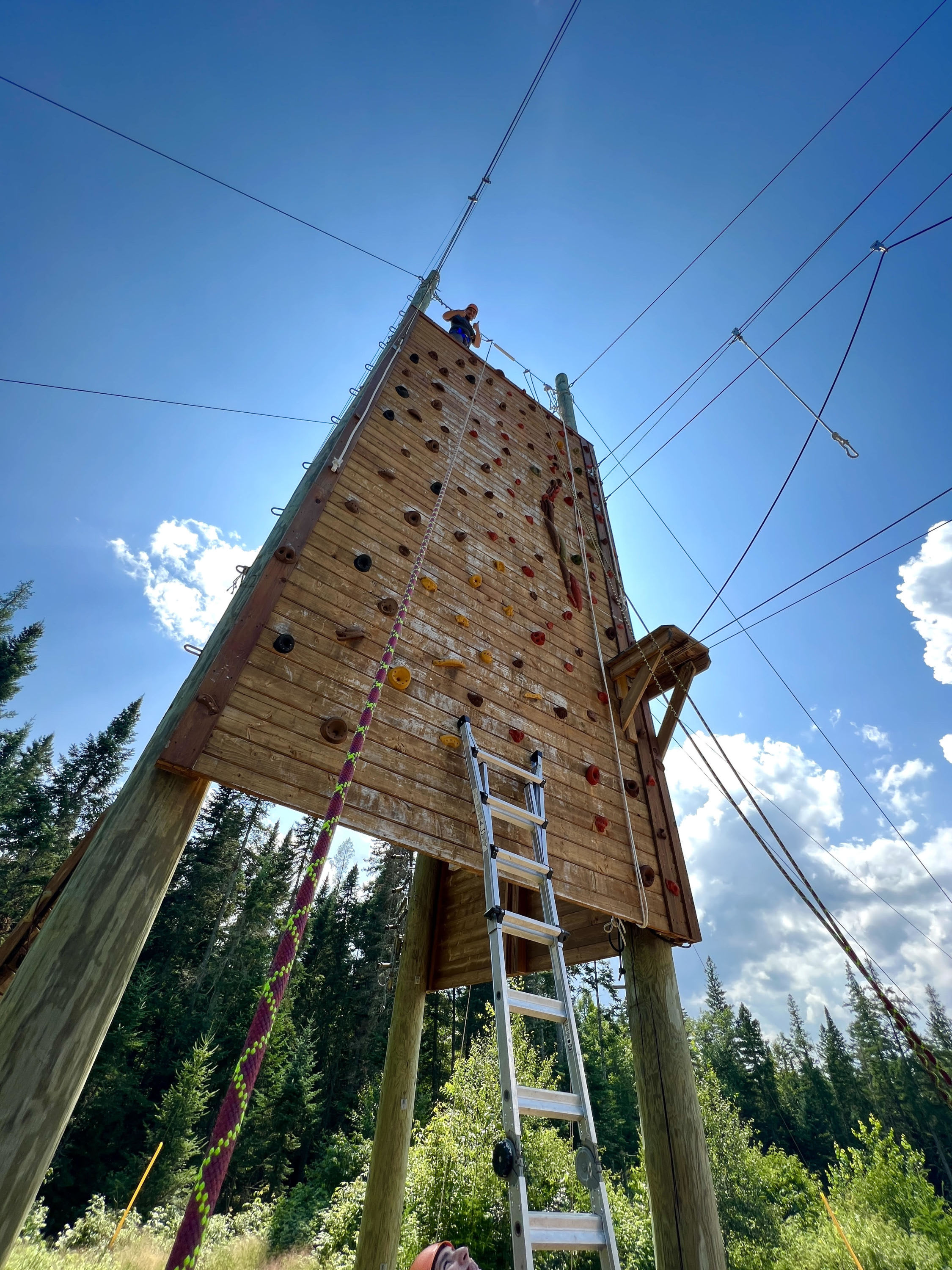 A student celebrates their ascent of the rock wall on campus.