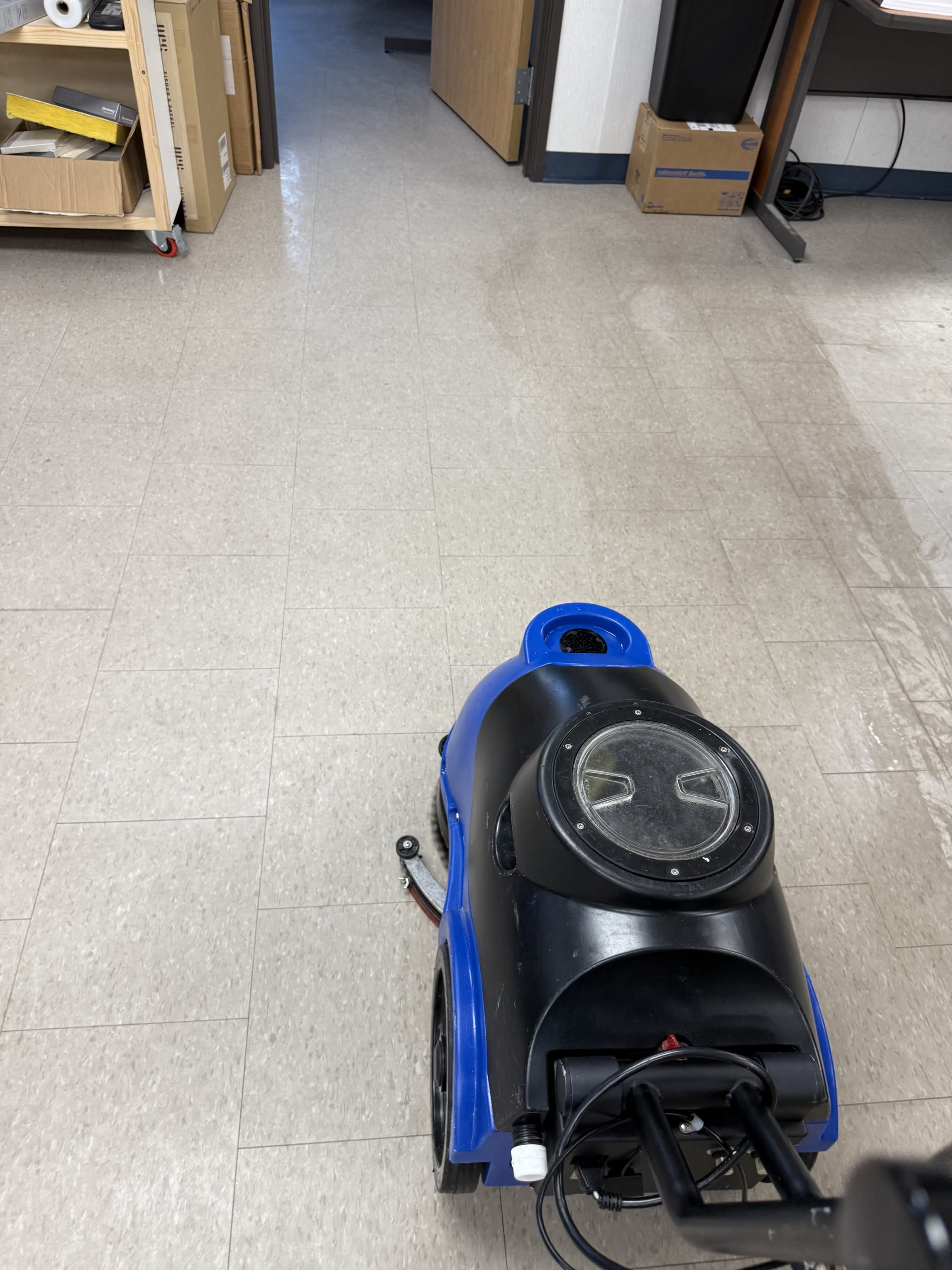 ommercial floor scrubber machine cleaning office vinyl tile flooring, leaving a polished surface behind.