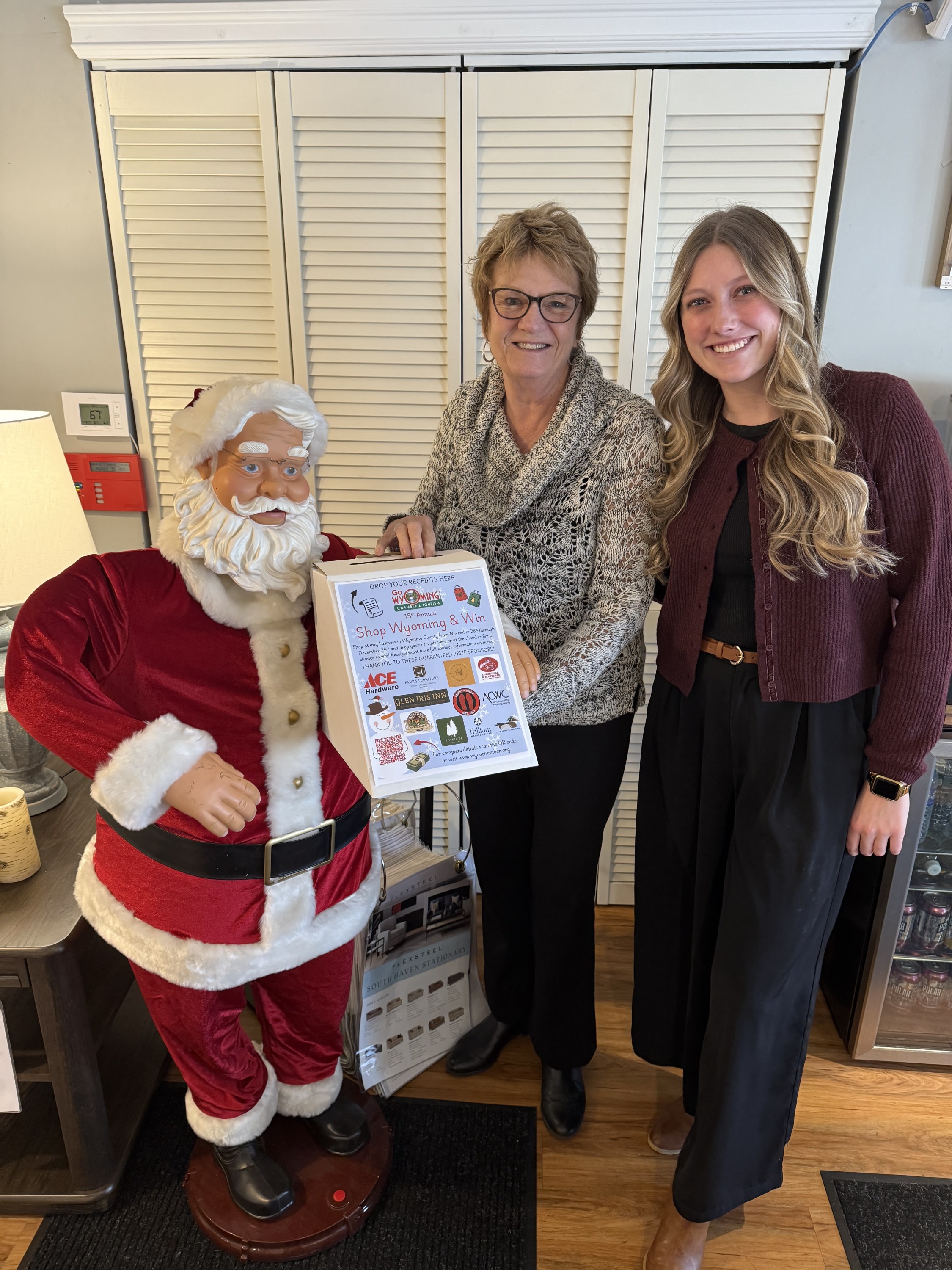 two people holding the shop wyoming and win box next to santa figure