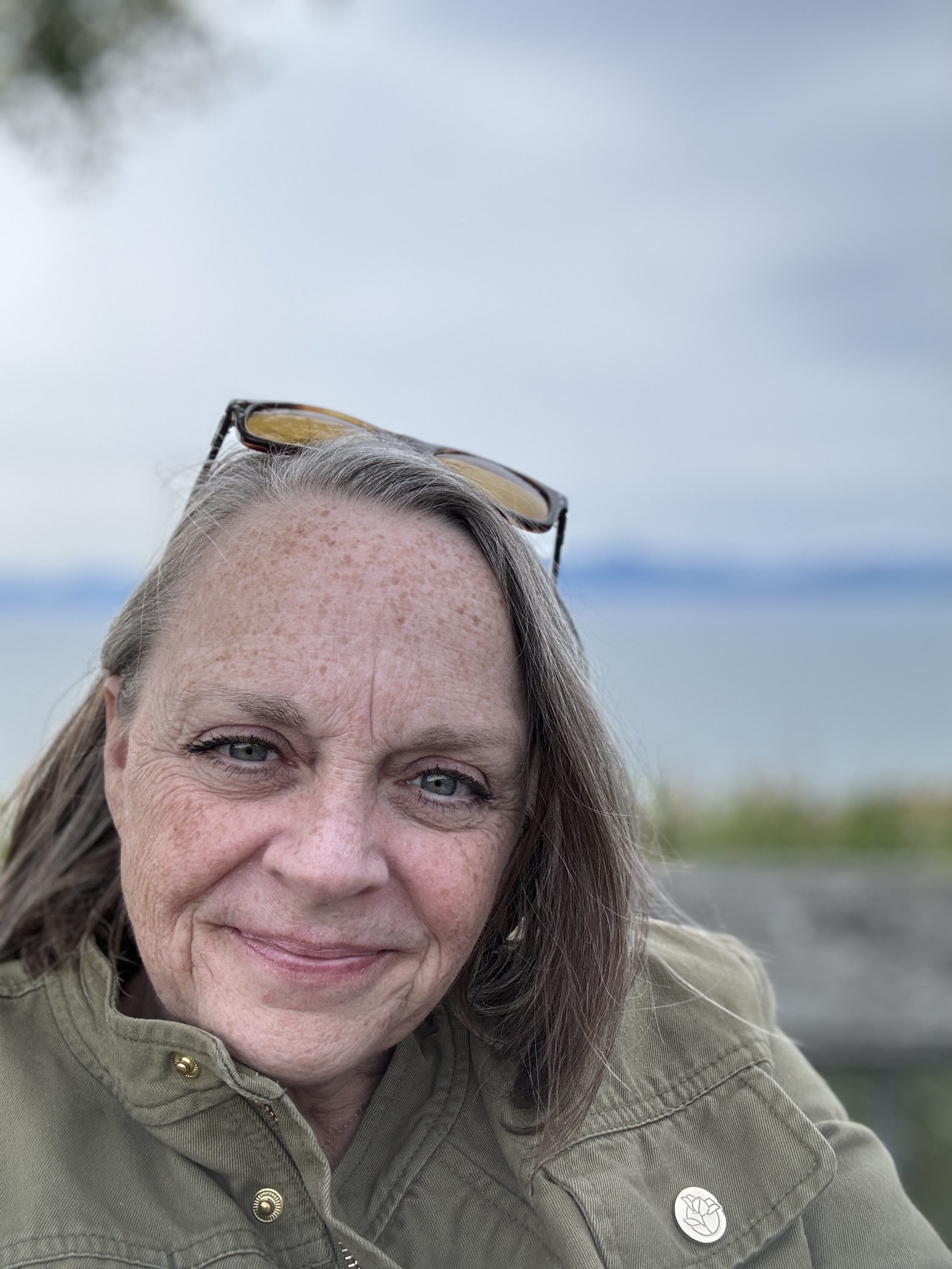 Kaylan is a middle aged white woman with freckles, blue eyes, and brown hair in a chin-length bob