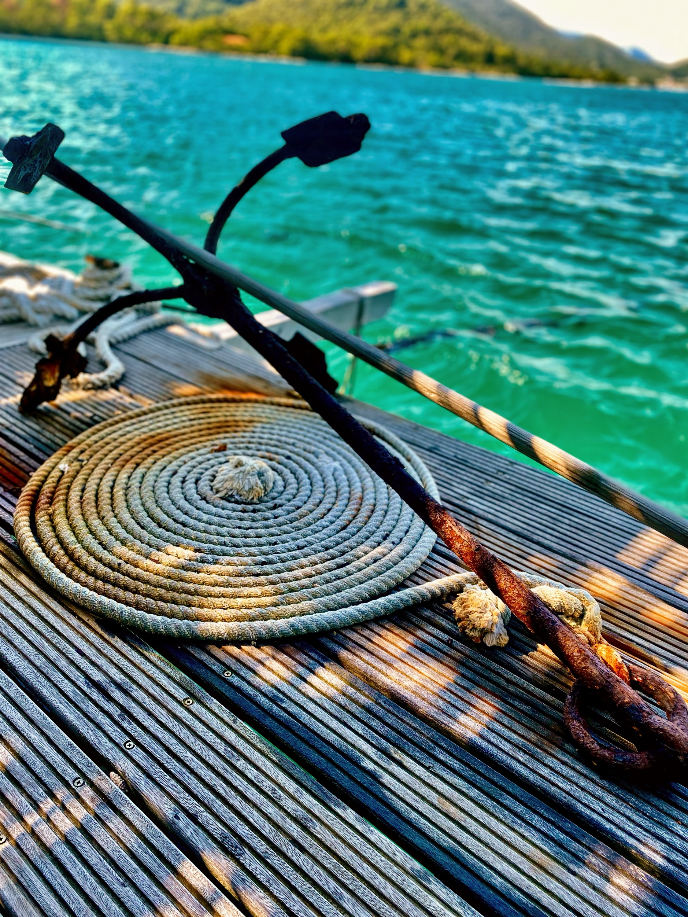 Old boat anchor on a dock with coiled rope