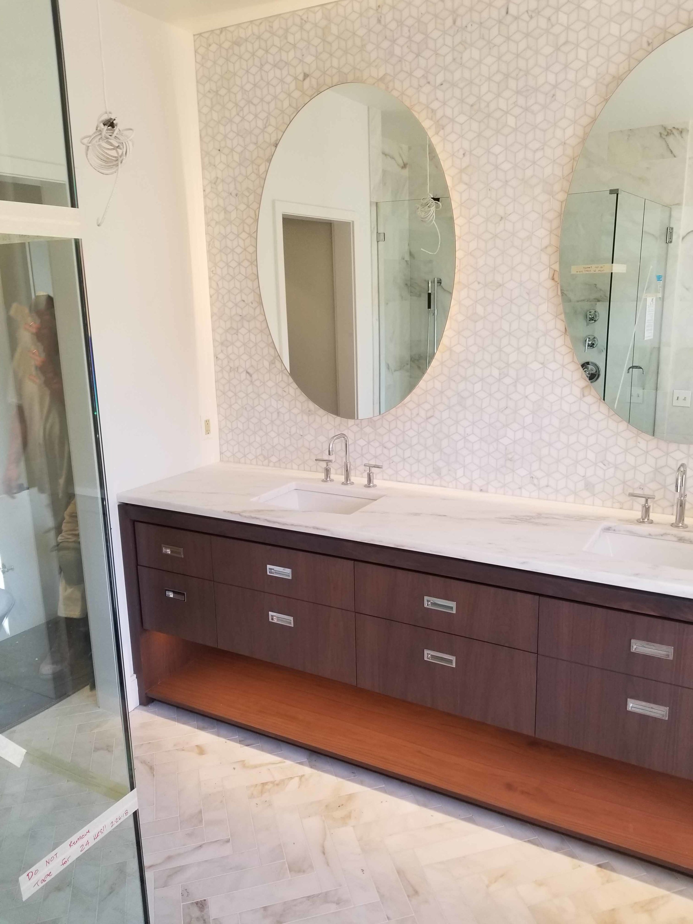 A modern bathroom features a dark wood double vanity with a white marble countertop and integrated sinks.