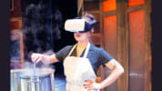 Woman wearing VR headset stirring something in a steaming steel pot