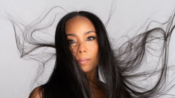 A picture of a woman with long black hair who looks directly in the camera.