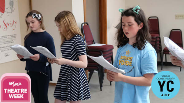 Students read lines from a script in a classroom setting.