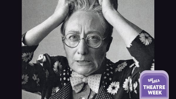 Black and white photo of Terry Baum with her hands in her hair. Terry wears round glasses and a floral polkadot suit.