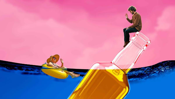 A large bottle of liquor floats in blue water against a pink sky, with a young man sitting atop the bottle, smiling and wavin
