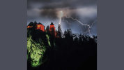 haunted house on a tall hill during a lightning storm
