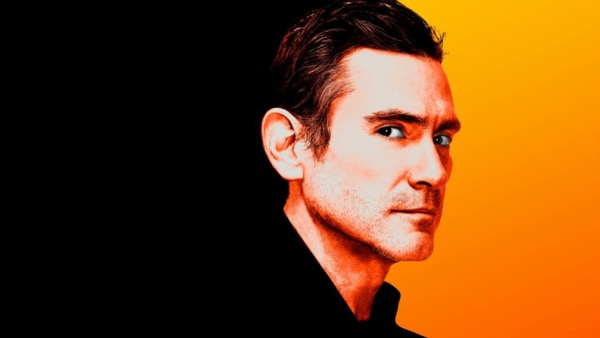 White male face with short dark hair against a 2/3 black 1/3 orange background