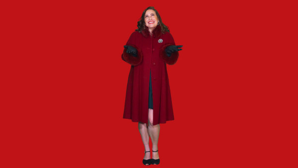 a brunette white woman in a red coat and black gloves smiles up at the sky
