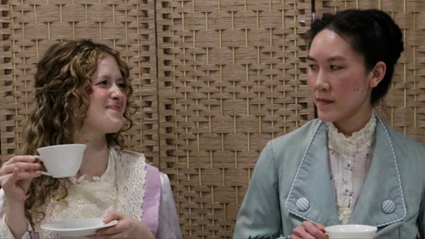 Two women with tea cups one white woman with blonde hair and one asian woman with black hair