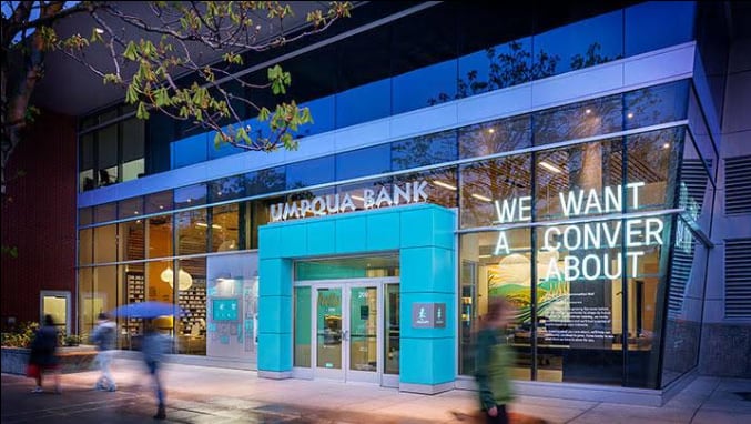 Exterior of Umpqua Bank South Lake Union at dusk with modern glass facade, blue entrance, and visible signage.