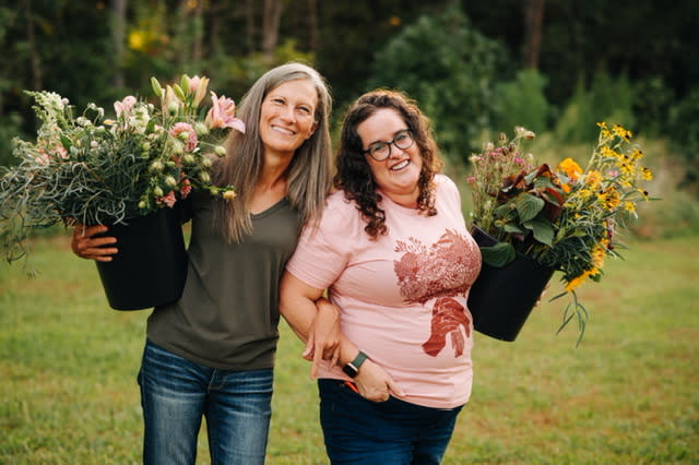 Karin and Emily, owners of Tova Cotton, holding buckets of their farm grown flowers