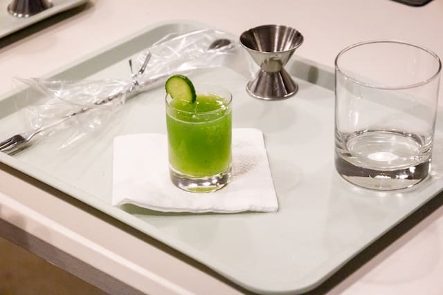 A neatly arranged tray featuring a small green ENAB garnished with a cucumber slice, placed on a white napkin.