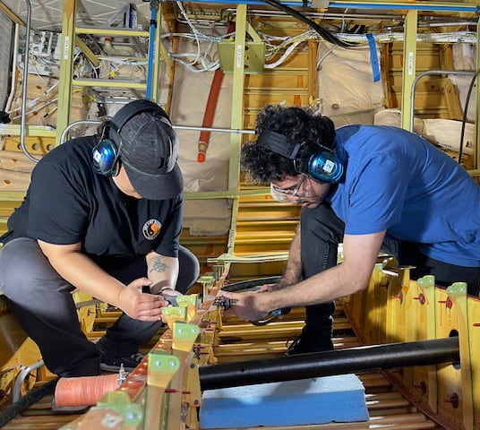 2 people working on a fuselage mechanical assembly