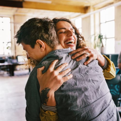 Two people hug each other in gratitude.