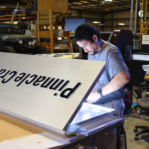 Assembly technician installing LED lighting in a sign.